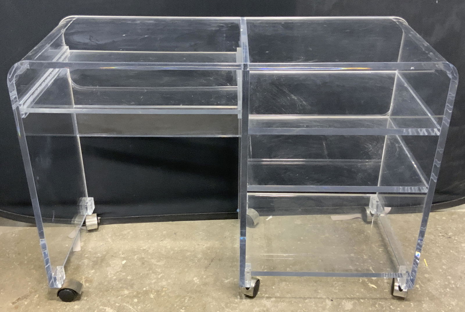 Vintage Mid Century Modern Lucite Wheeled Desk: A vintage mid century modern style wheeled desk. Crafted from chunky clear lucite. Six wheels to underside. Four storage areas. Piece above the kneehole is moveable, slides in and out. Some surface we