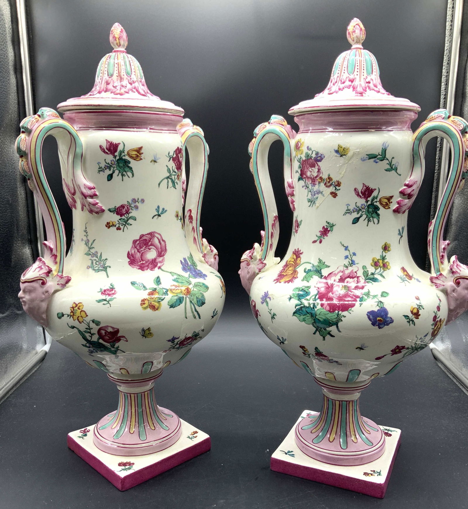 Pair GIEN Porcelain Floral Urns with Lids France: White porcelain Urns with lids, signed GIEN on verso. Made in France. Hand painted florals, Roses with neoclassical Features. Many pinks, greens, and aqua. Gargoyle faces on lower part of handle. Some