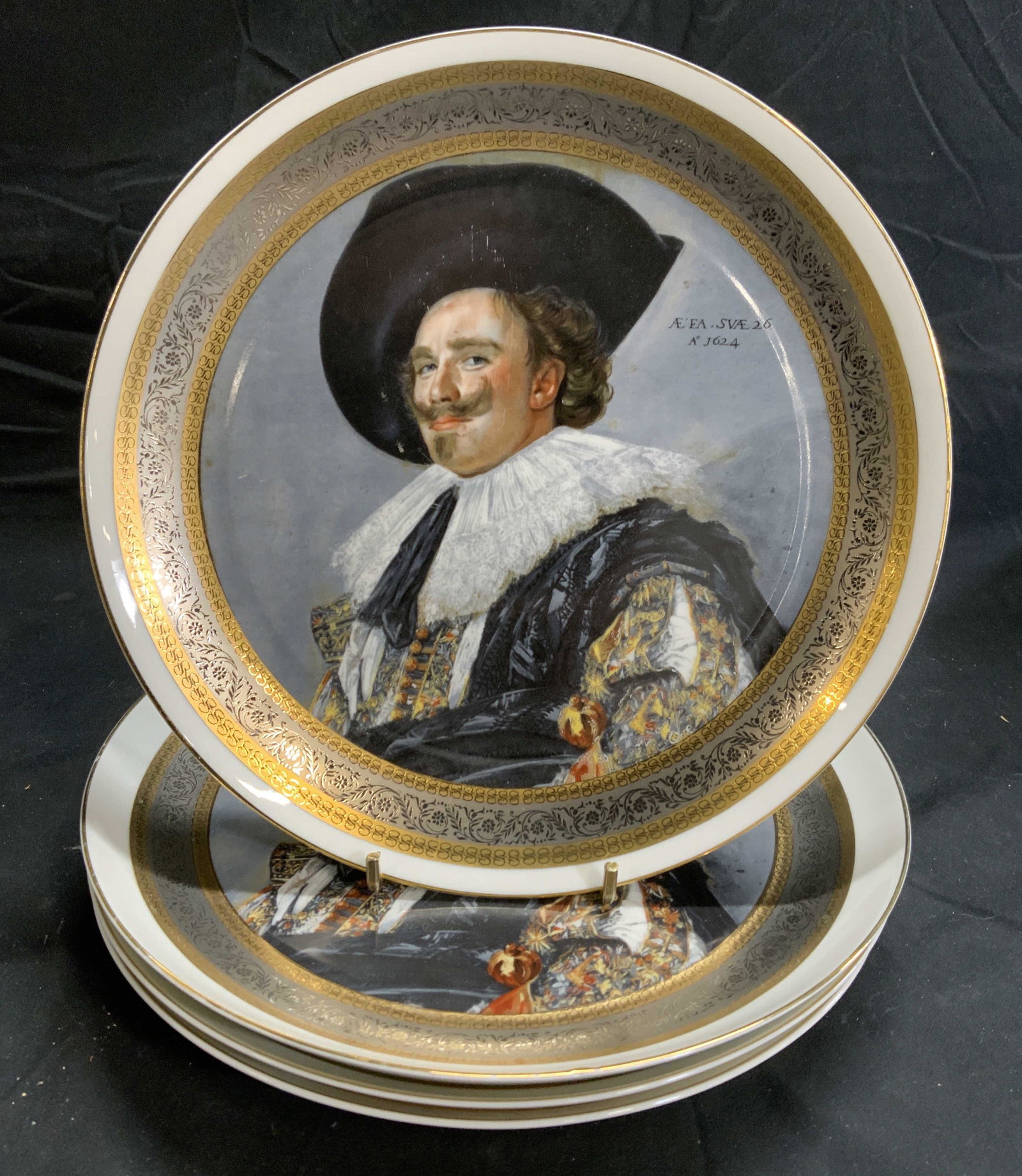Set 4 EME Porcelain Laughing Cavalier Plates Spain: Set of 4 EME porcelain plates with Laughing Cavalier decoration. Trademarked to undersides. Made in Spain. All pieces in good condition, minor wear to surface consistent with exposure. Hanging hardwar