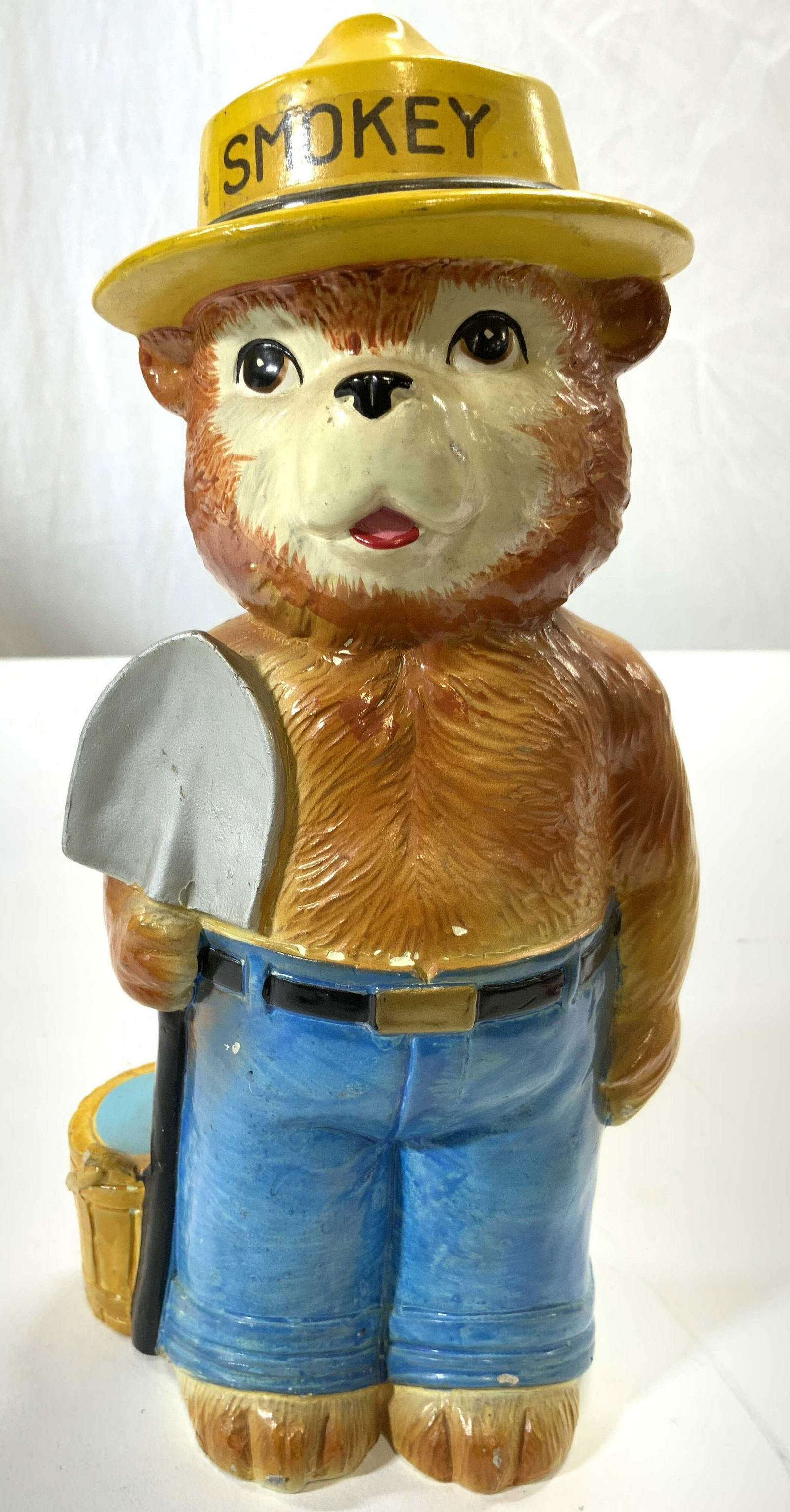 SMOKEY THE BEAR Vntg Piggy Bank: Piggy bank depicts SMOKEY THE BEAR character wearing hat which reads SMOKEY. Piece is a lightweight composite material. Backside of piece has coin slot. Piggy bank is possibly hand painted. Measures a