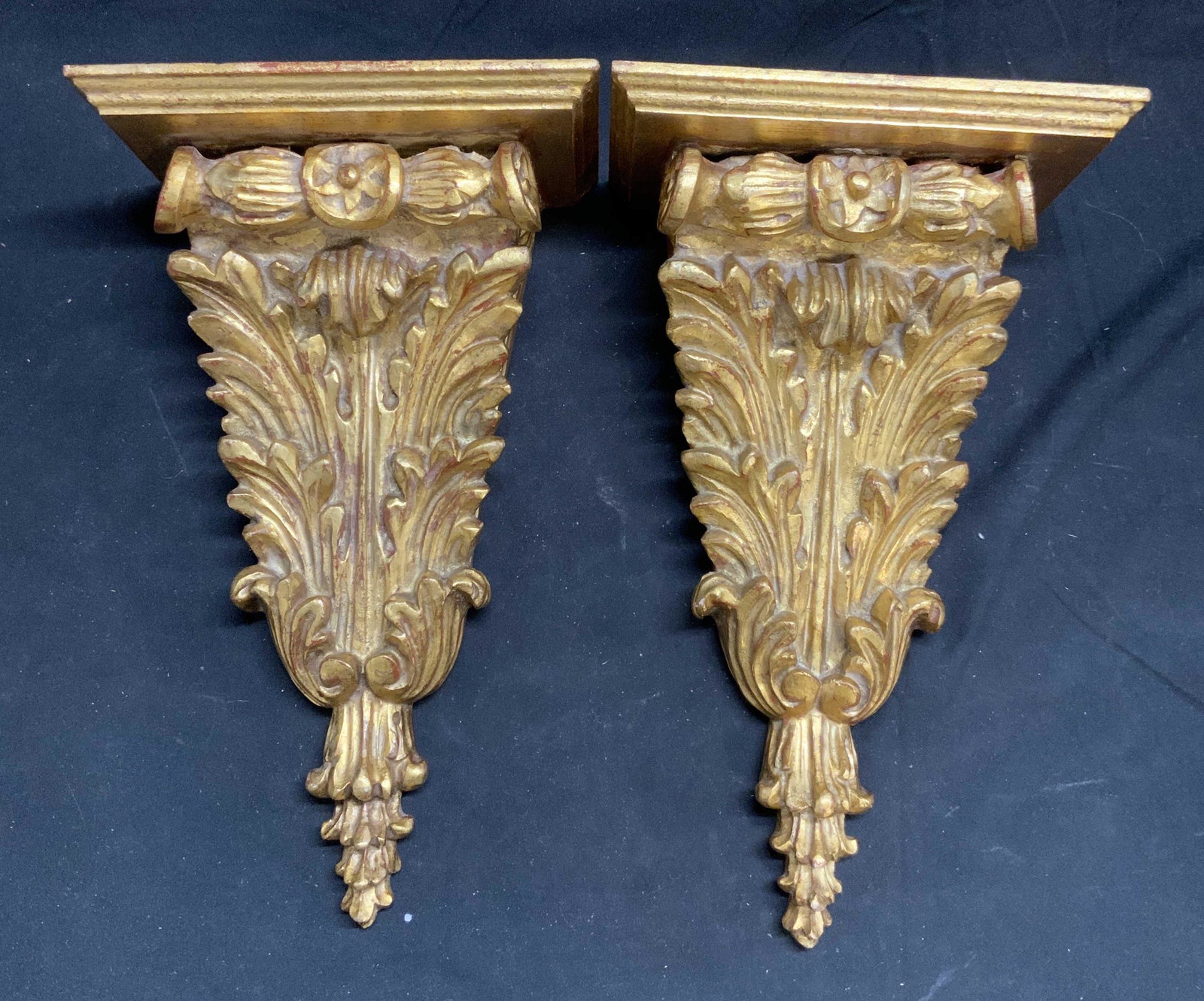 Pair Gilt Wood Fleur De Lis Accent Shelves, Italy: Pair of gilt wood accent shelves with scroll/fleur de lis motif. Marked made in Italy to underside. Surface wear consistent with exposure, some loss to paint. Measure approx. 13 inches tall, 7.5 inche