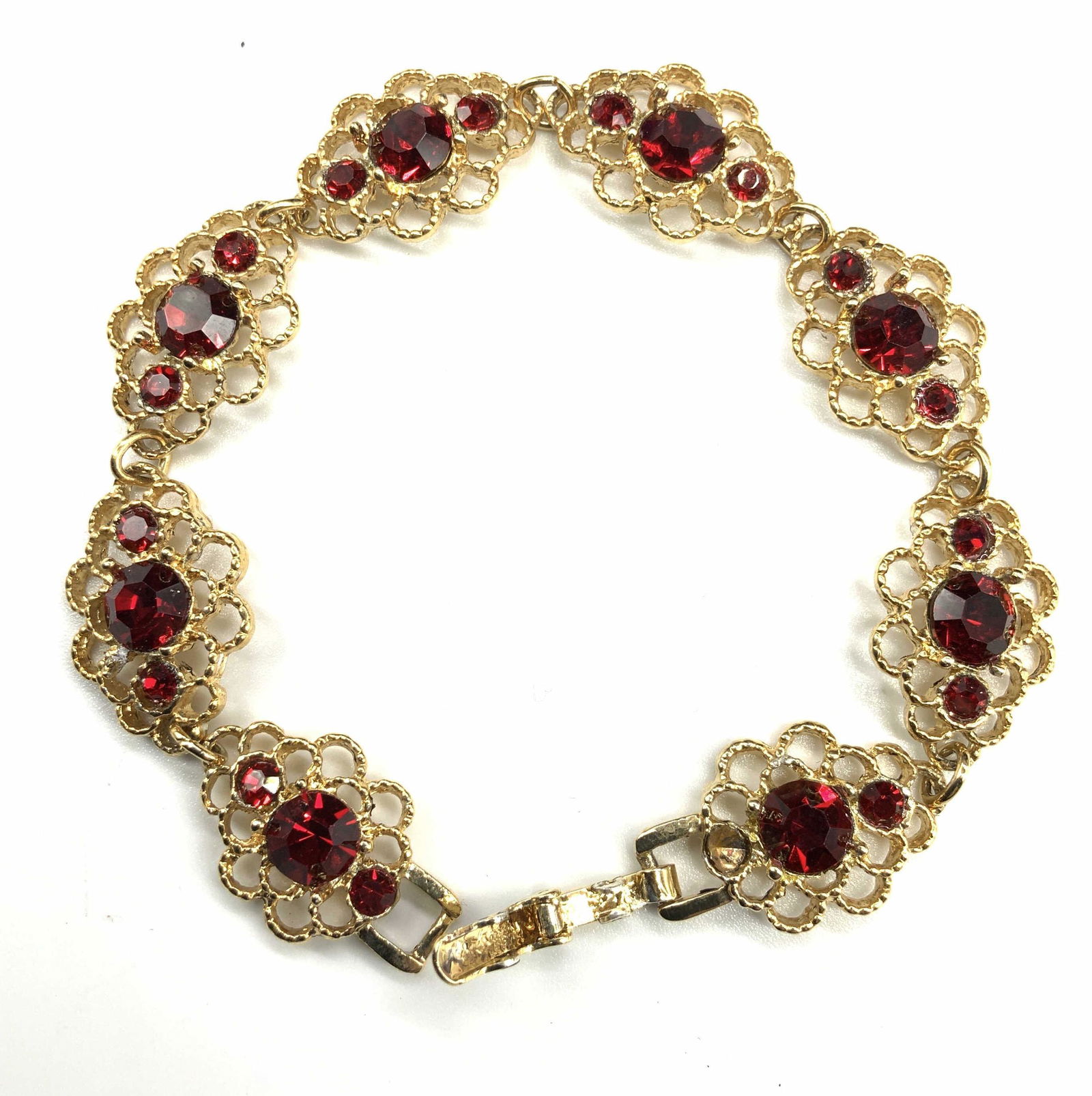 Gold tone & Red Crystal Bracelet: Open circle floral style links in gold tone with 3 red crystal center. 7.25 in long, 1/2 in wide. Hallmarked Made in USA. 1 missing crystal, unremarkable. Luxury Estate Jewelry, Luxury vintage Jewelry