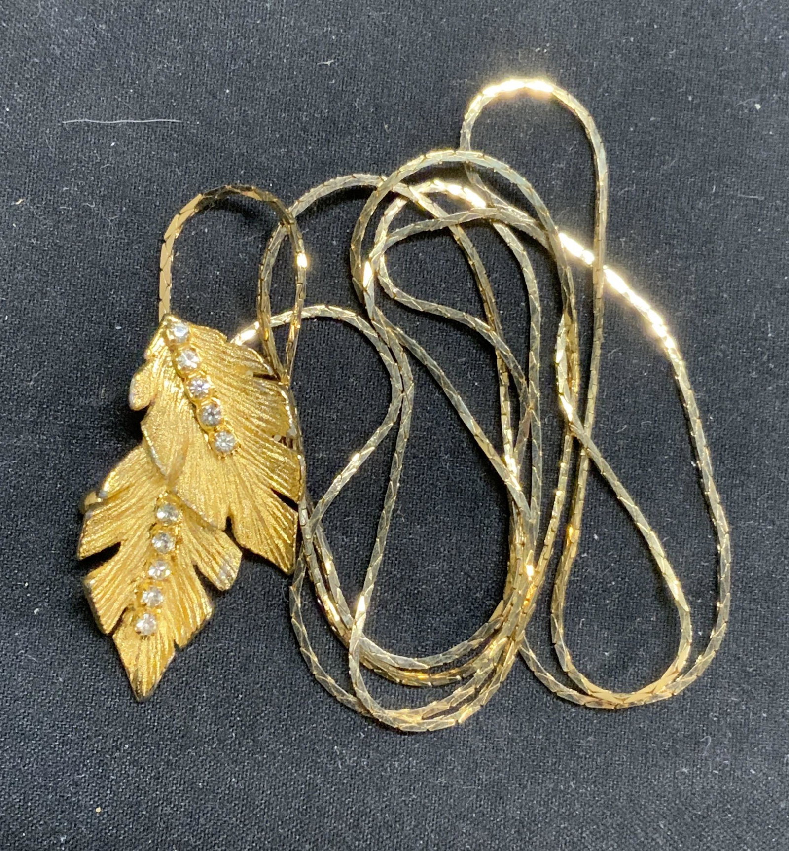 Gold Tone Leaf Pendant Necklace, Jewelry: Gold tone snake chain necklace with leaf form pendant and crystal decoration. Measures approx. 28.5 inches long. Pendant measures approx. .75 x 1 3/8 inches. Property of Palm Beach, Florida estate. Es