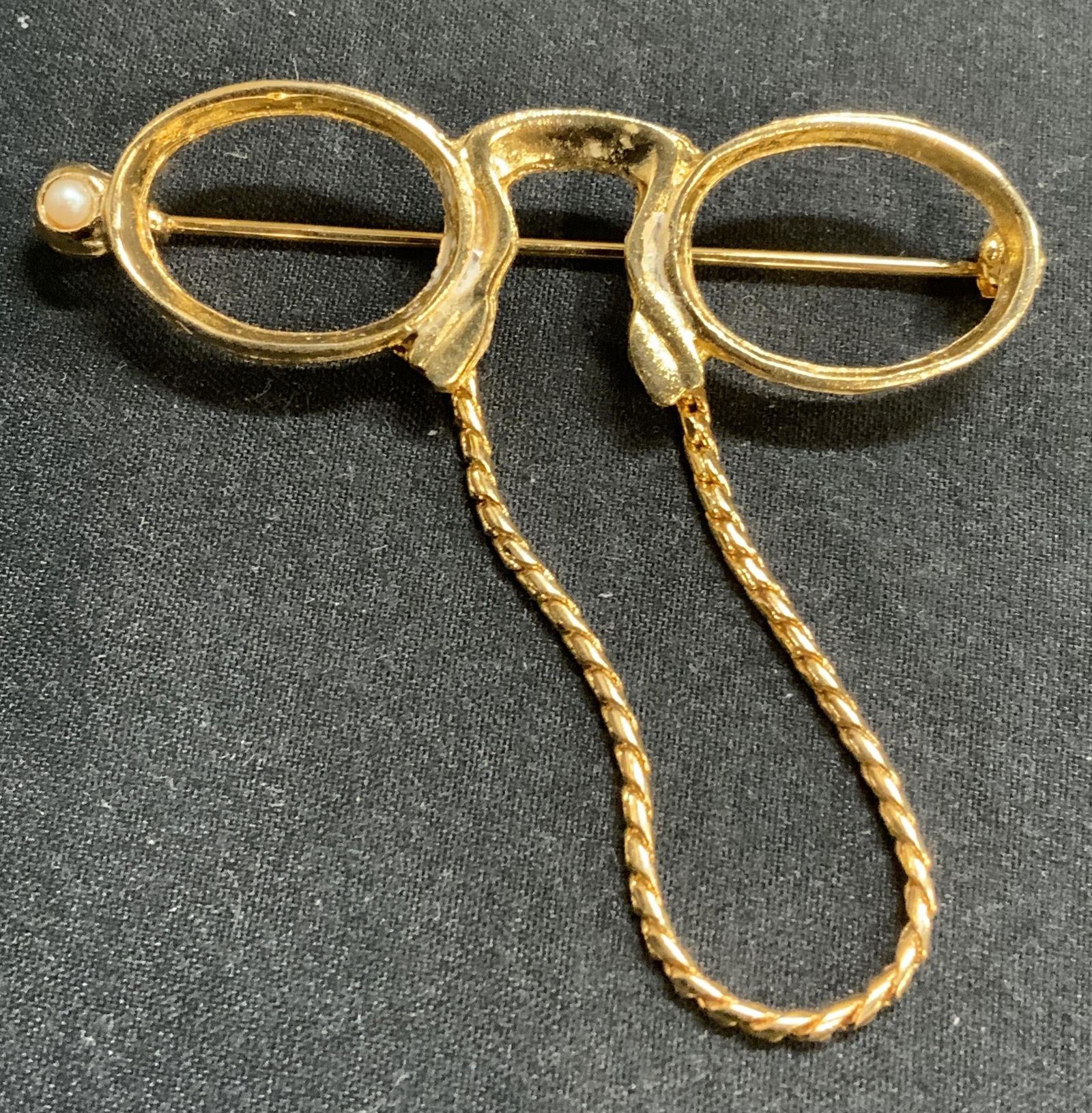 Signed Gold Tone Glasses Brooch, Jewelry: Gold tone glasses brooch with chain and faux pearl decoration. Hinge pin to underside. Signed to underside, illegible. Measures approx. 2.25 x 2 inches. Some surface wear consistent with exposure. Est