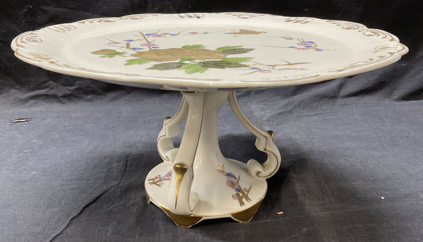 Porcelain Gold Tn Detailed Cake Stand: Porcelain Gold Tn Detailed Cake Stand. Surface has floral detail, with gold tone detail. Measures approx 12.25 x 6 inches. Prior repair to piece. Painted number on underside, labeled 6638. Cake stand,
