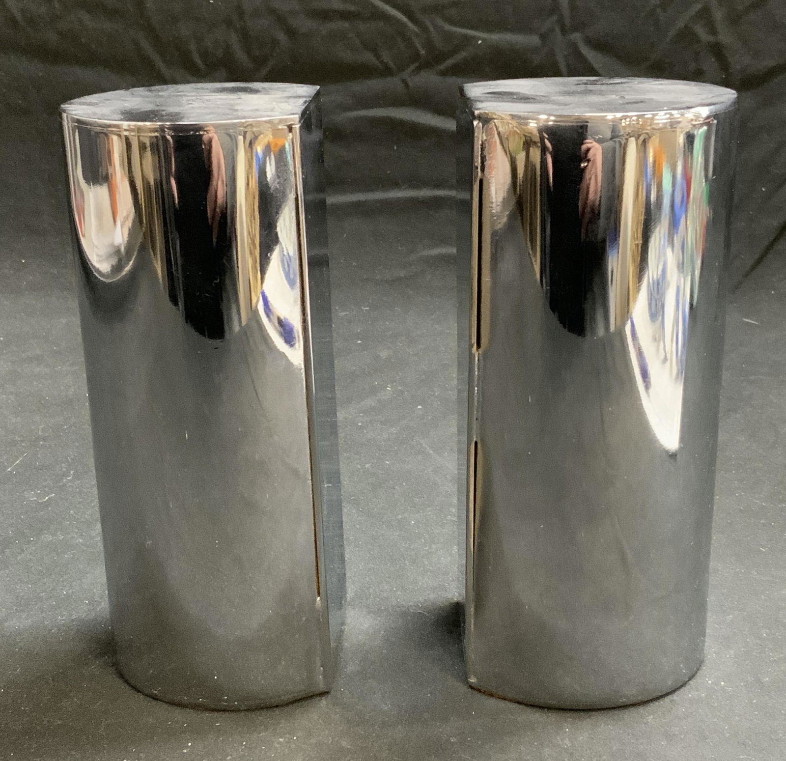 Pair Cylindrical Chromed Metal Bookends: Pair of chromed metal bookends. Pieces are weighted. Measures approx. 2 3/8 x 2 5/8 x 6 inches. Some surface wear consistent with exposure. Bookends, metal bookends, chromed bookends. Weighted bookend