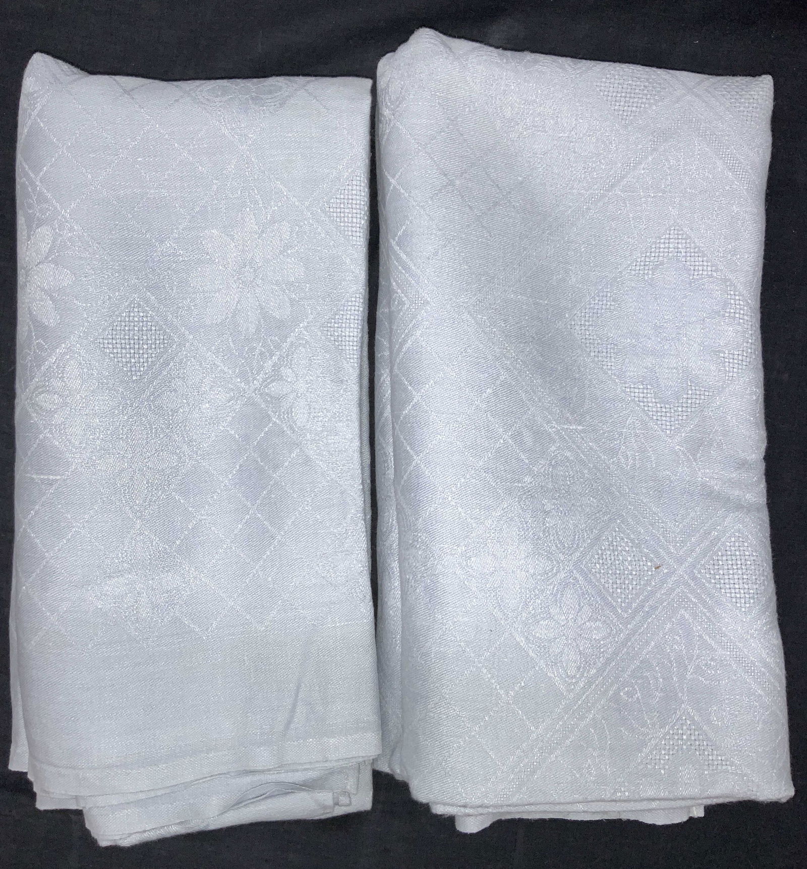 Baby Blue Toned Floral Table Cloths: Pair of baby blue toned table cloths, approximately 58 x 64 inches, both adorn with subtle floral motifs and hatching stitching. Evident blemishes to cloth, Floral table cloths, table cloths, blue, ba