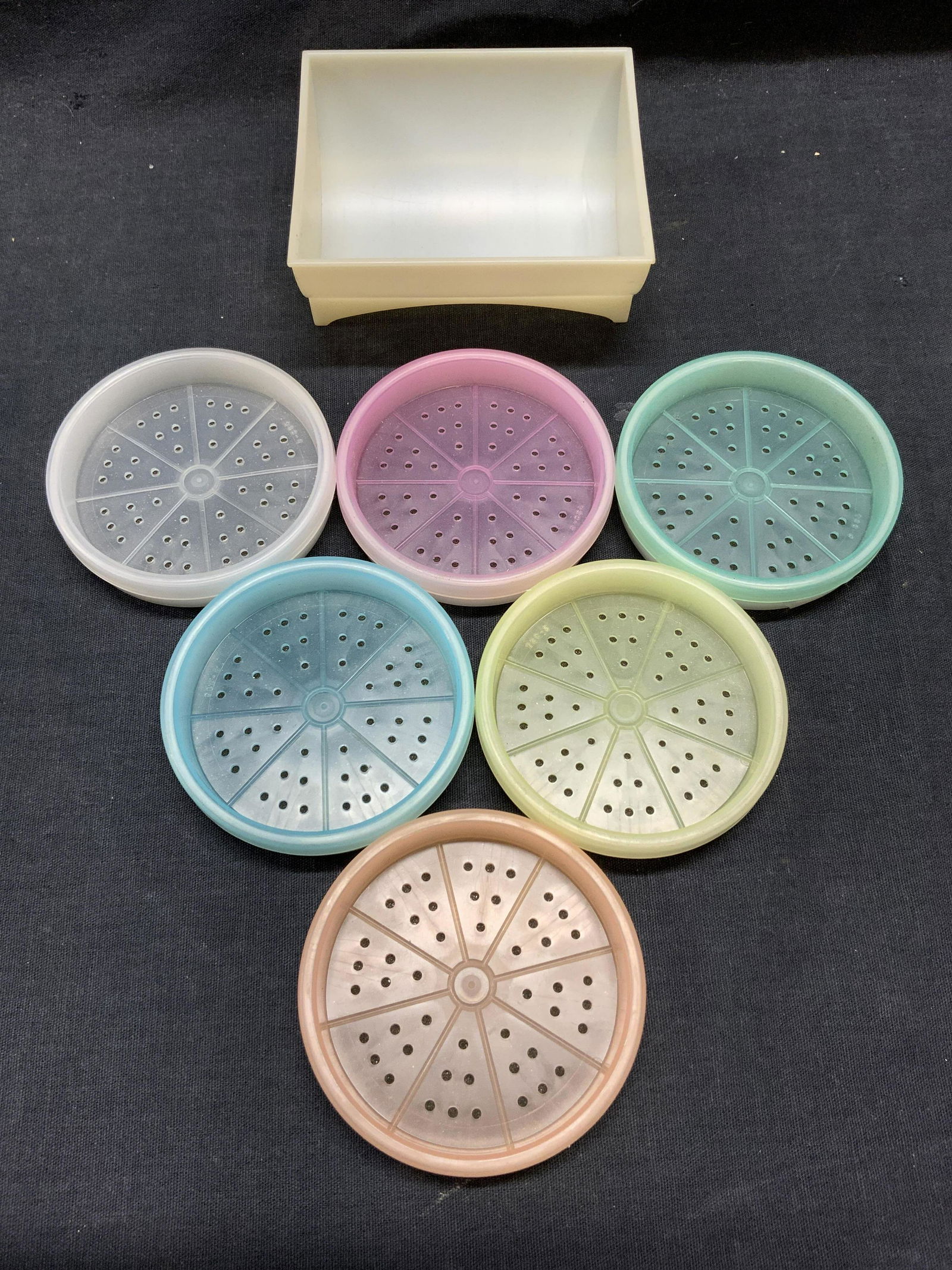 TUPPERWARE Set 7 Coasters & Holder: Underside of each coaster reads TUPPERWARE. Lot includes 6 coasters and coaster holder. Coasters in vary in color. Coaster holder measures approx 3.75 inches long 3.25 inches wide 1.5 inches tall. Coa