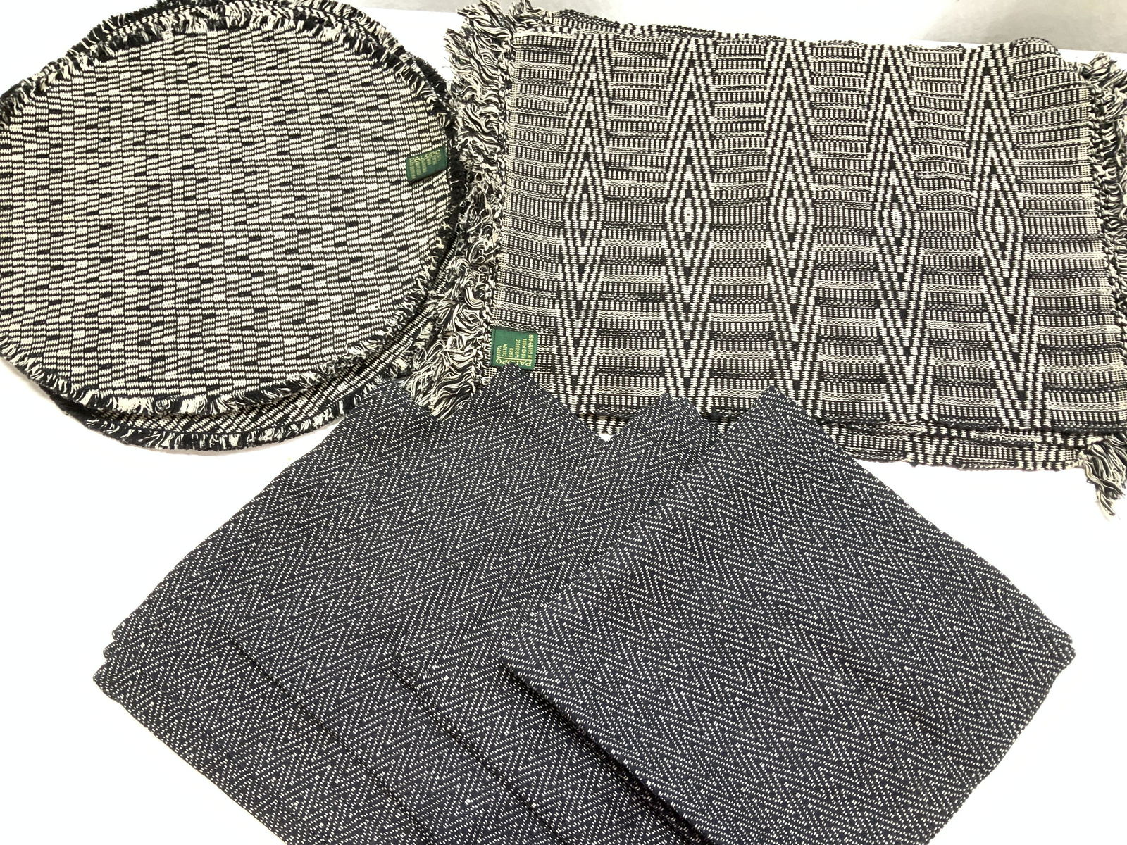 Lot 14 Placemats, Napkins & Tablecloth: Black and white table linens. 4 round Palopo cotton placements, 15 in. 4 Palopo Geo print tapestry style placemats with end fringe. 20 x 14 in. 1 black rayon square tablecloth , 52 x 51 in. Machine em