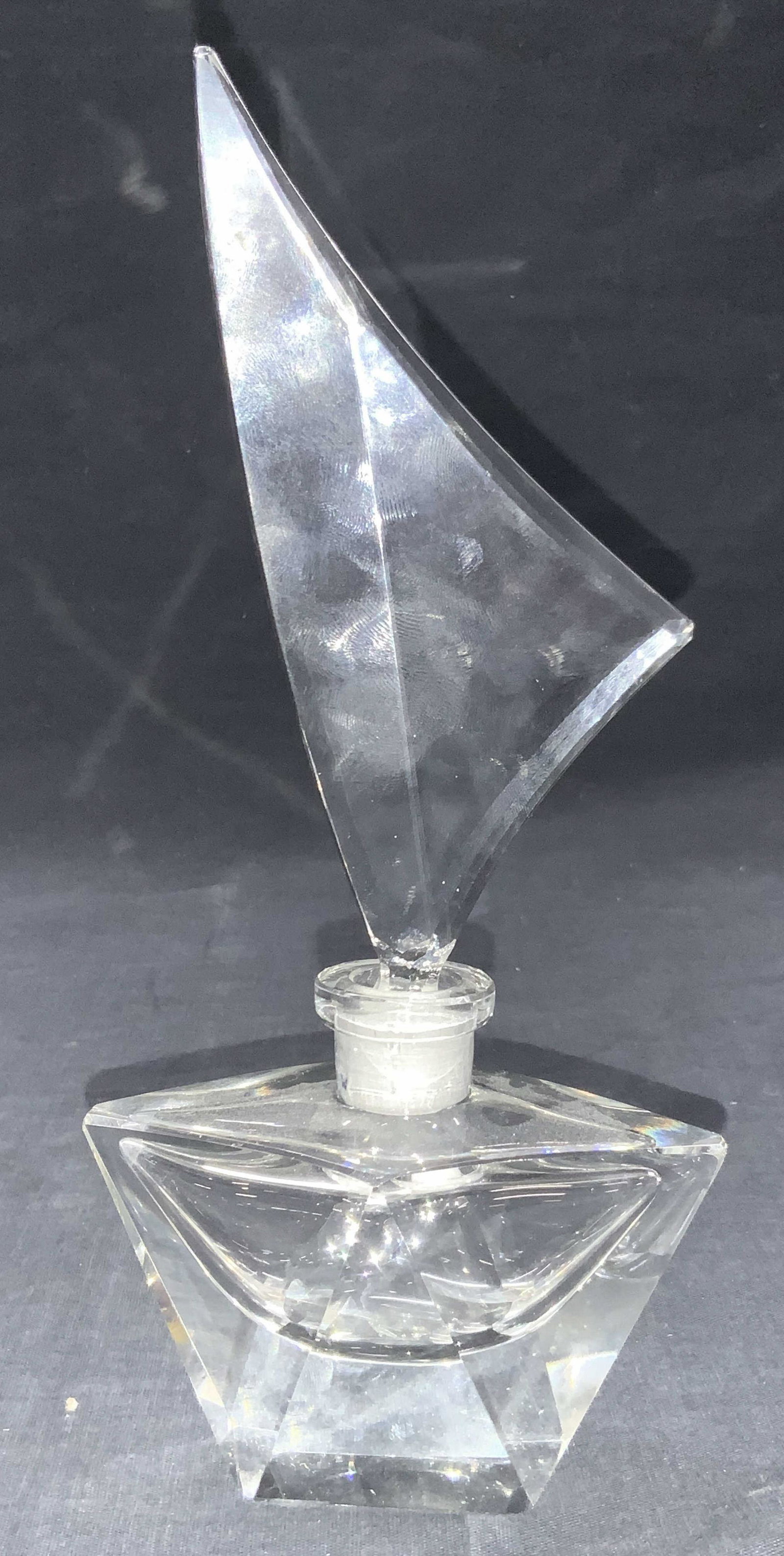 Sail Boat Style Clear Glass Bottle: Clear glass perfume bottle resembling a sail boat with extended triangular shaped stopper. Approximately 9 inches tall and 4.5 inches long Minor chipping to some areas. Sail boat bottle, glass bottle.