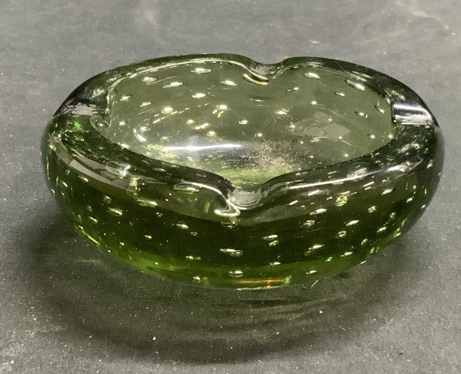 Green Bubble Art Glass Ashtray, England: Green bubble Art glass ashtray. Some surface wear consistent with exposure. Measures approx. 4 inches diameter and 1.5 inches tall. Marked England to underside. Art glass, Studio glass, bubble glass, 