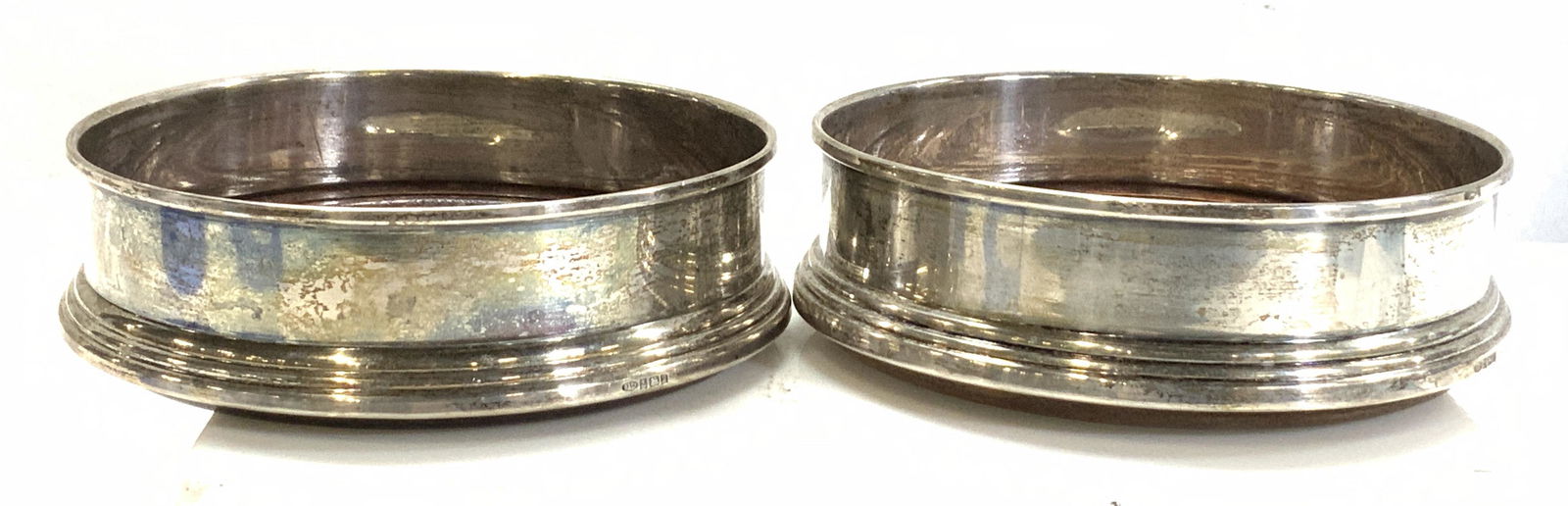 Pair B&C Sterling Silver Champagne Bottle Coasters: Hallmarked Sterling Silver and Wood Champagne or wine bottle Coasters, hallmarked B&C anchor , lion and U Passants. Some wear to wood. Underside lined with felt. 4.5 in diameter, 1.5 in ht. 9.90 ozt t