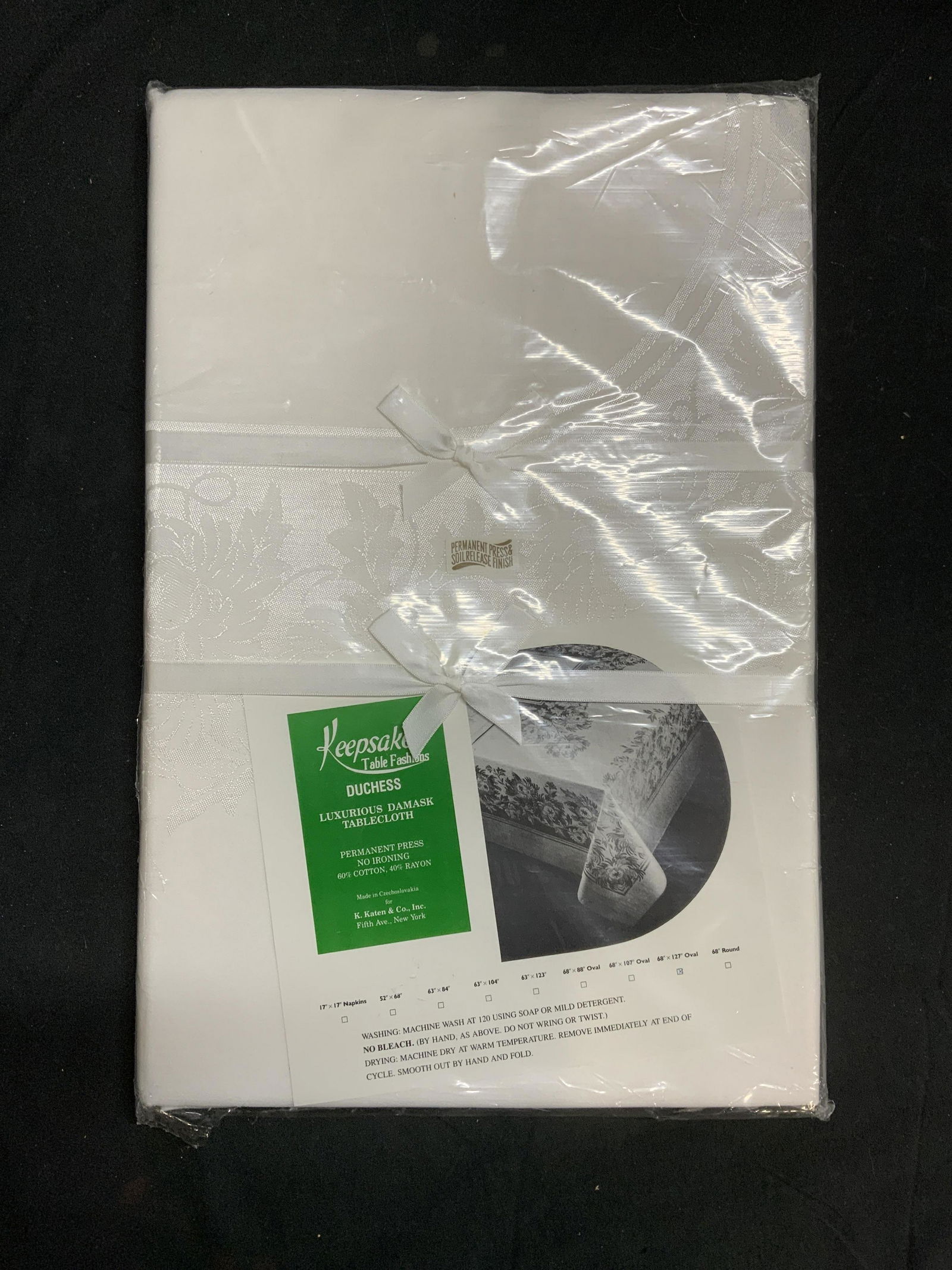 Keepsake Table Fashion Damask Tablecloth NIP: Keepsake Table Fashions Duchess Damask tablecloth in white. Oval shaped, measures 68 x 127 inches. New in packaging. Not removed from packaging. Cotton and rayon blend. Keepsake table fashions, duches
