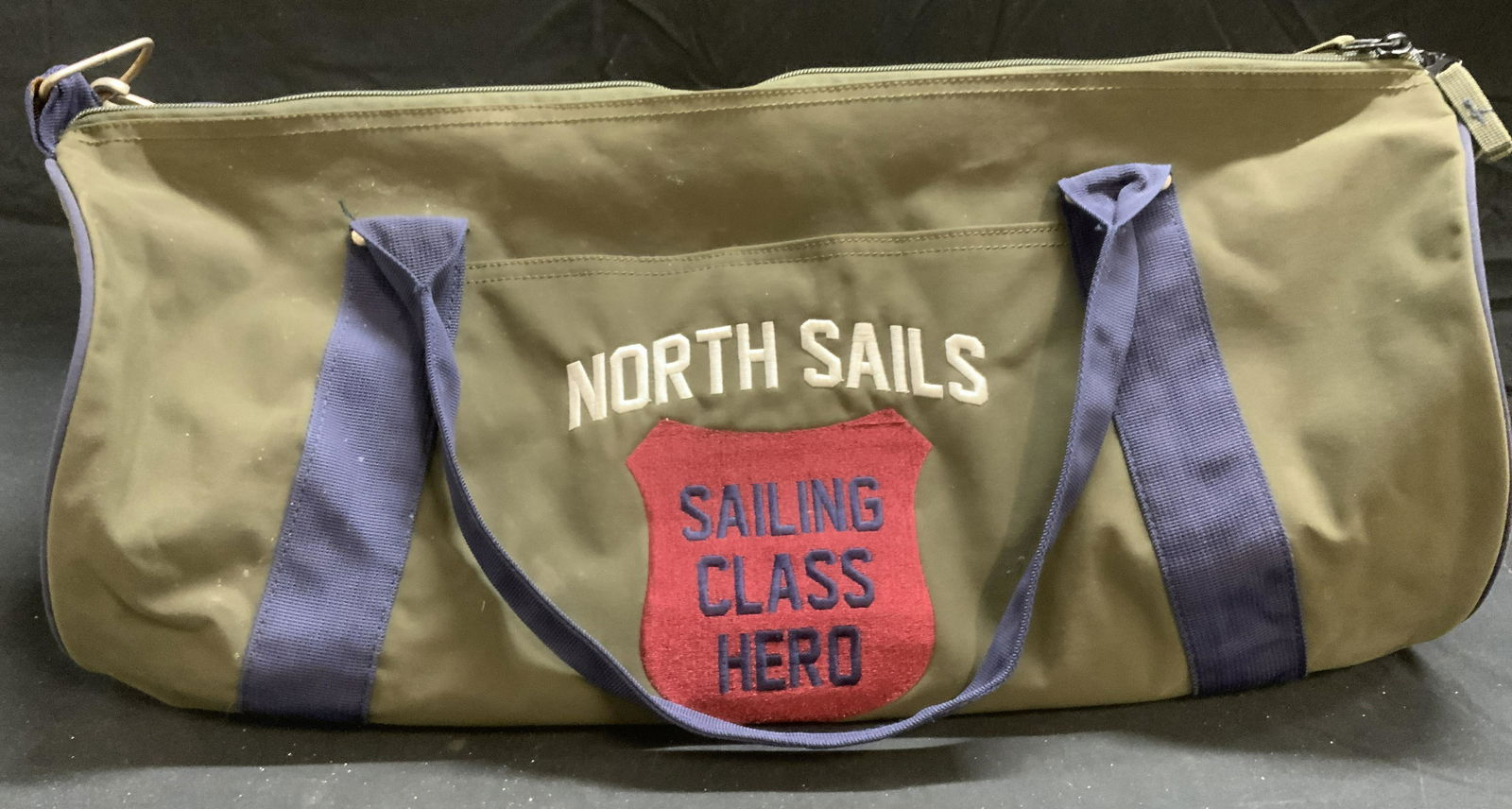 North Sails Sailing Class Hero Green Duffel Bag: North Sails Sailing Class Hero green cotton duffel bag with blue trim. Measures approx. 22.5 x 11.5 x 10 inches. Surface wear consistent with exposure. North sails, sailing bag, sailing class hero, gr