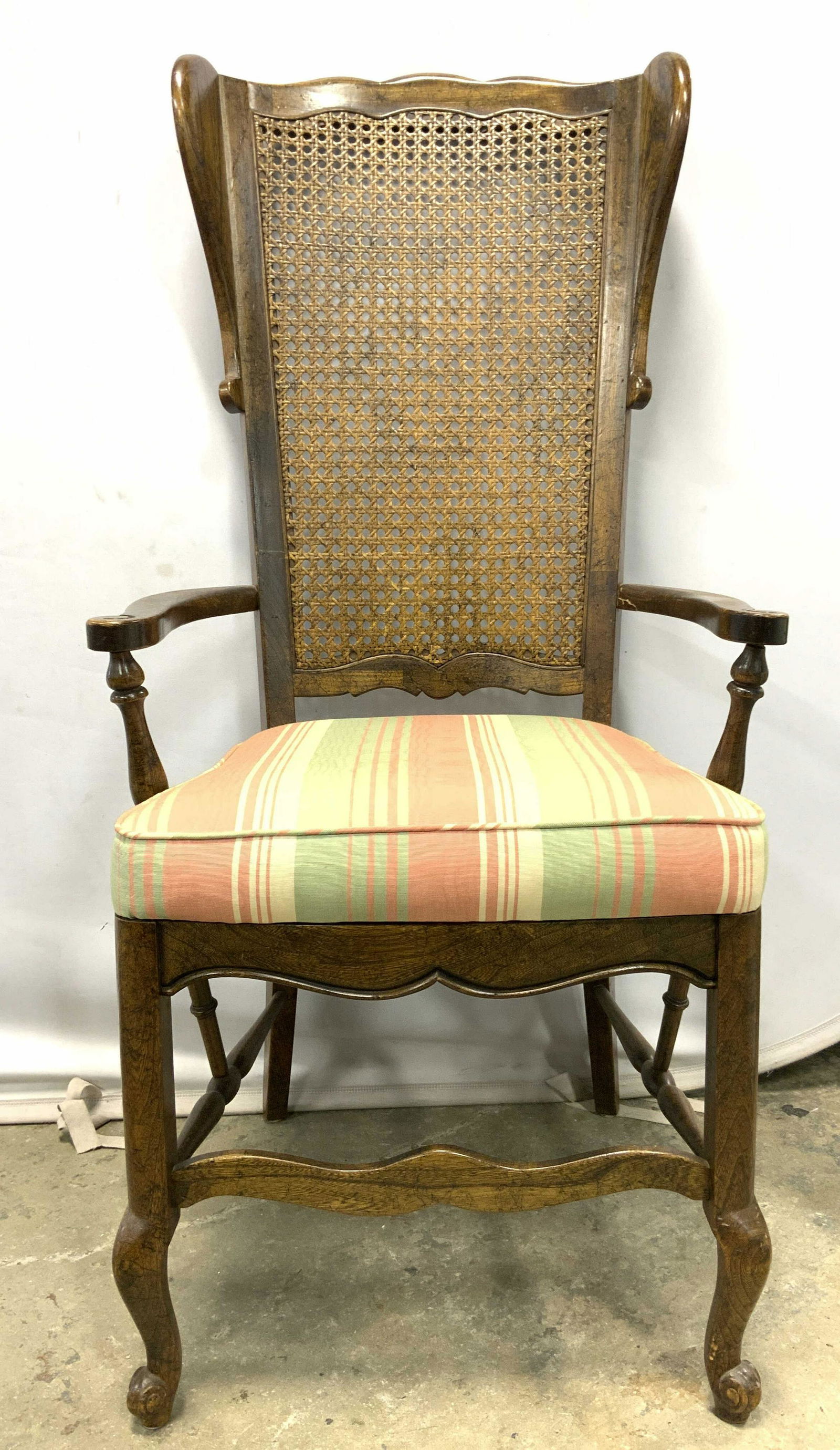 Vntg Carved Wooden Caned Wingback End Chair: Chair is vintage and woode. Piece had caned winged backrest 3 toned striped seat cushion & carved curled detailed front 2 legs. Legs have stretchers in between. Armrests also have carved curled detail