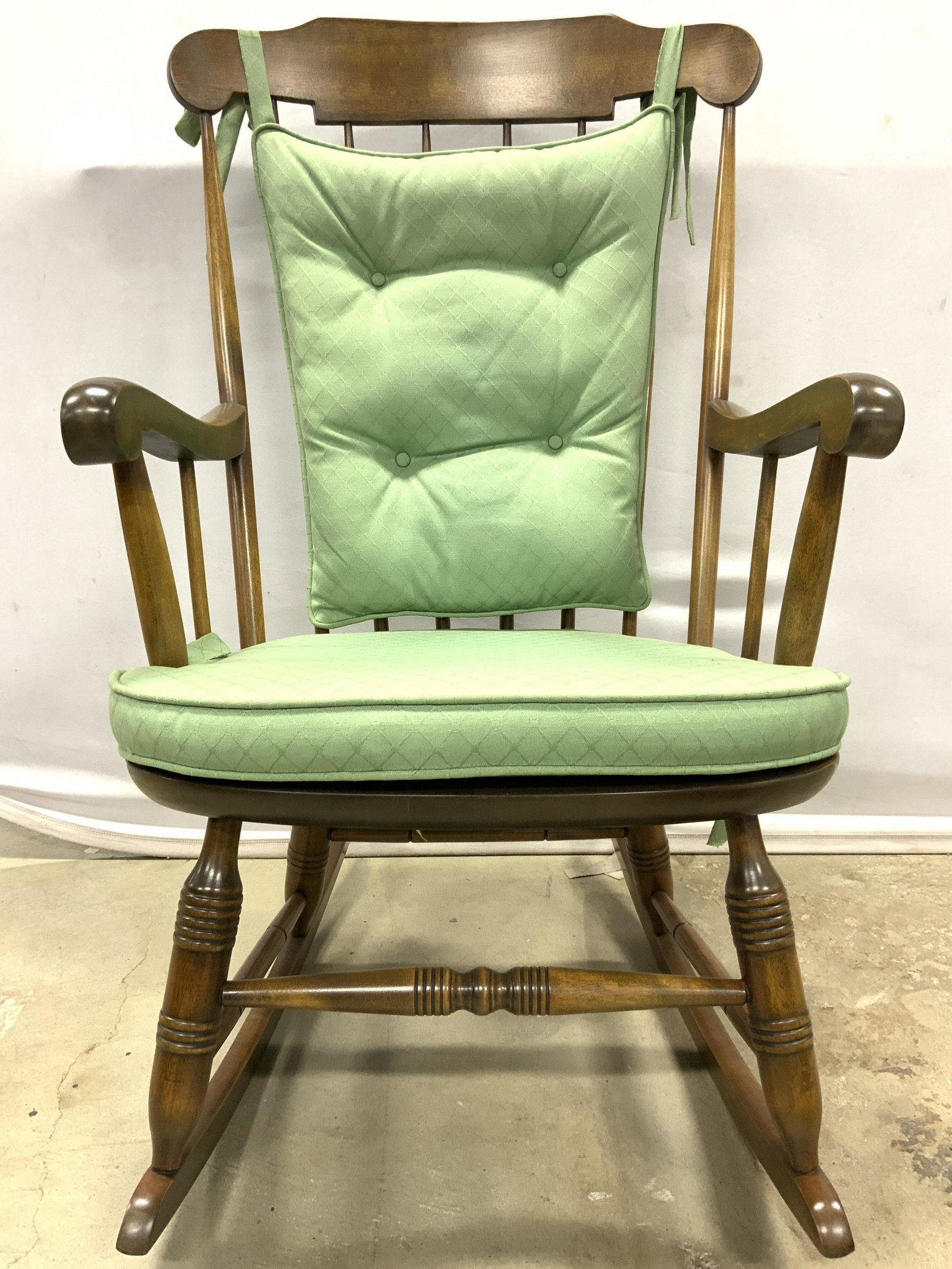 NICHOLS & STONE Vtg Spindleback Rocking Chair: Underside has tag which reads NICHOLS & STONE. Chair is wooden with Spindle backrest . Piece includes green toned tied diamond patterned cushions. Chair measures approx 40 inches tall 24 inches wide 2