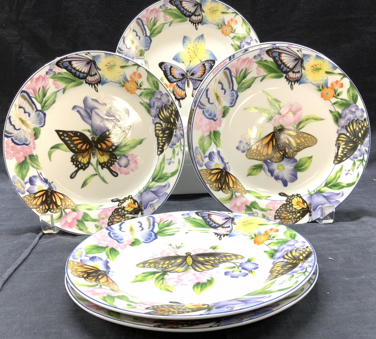American Atelier Butterfly Porcelain Plates, Set 8: Hand Painted white porcelain luncheon plates with colorful images of monarch butterflies and flowers., 8 in. Backside hallmarked American Atelier at Home Butterfly # 5090. 1 pair has a different butte