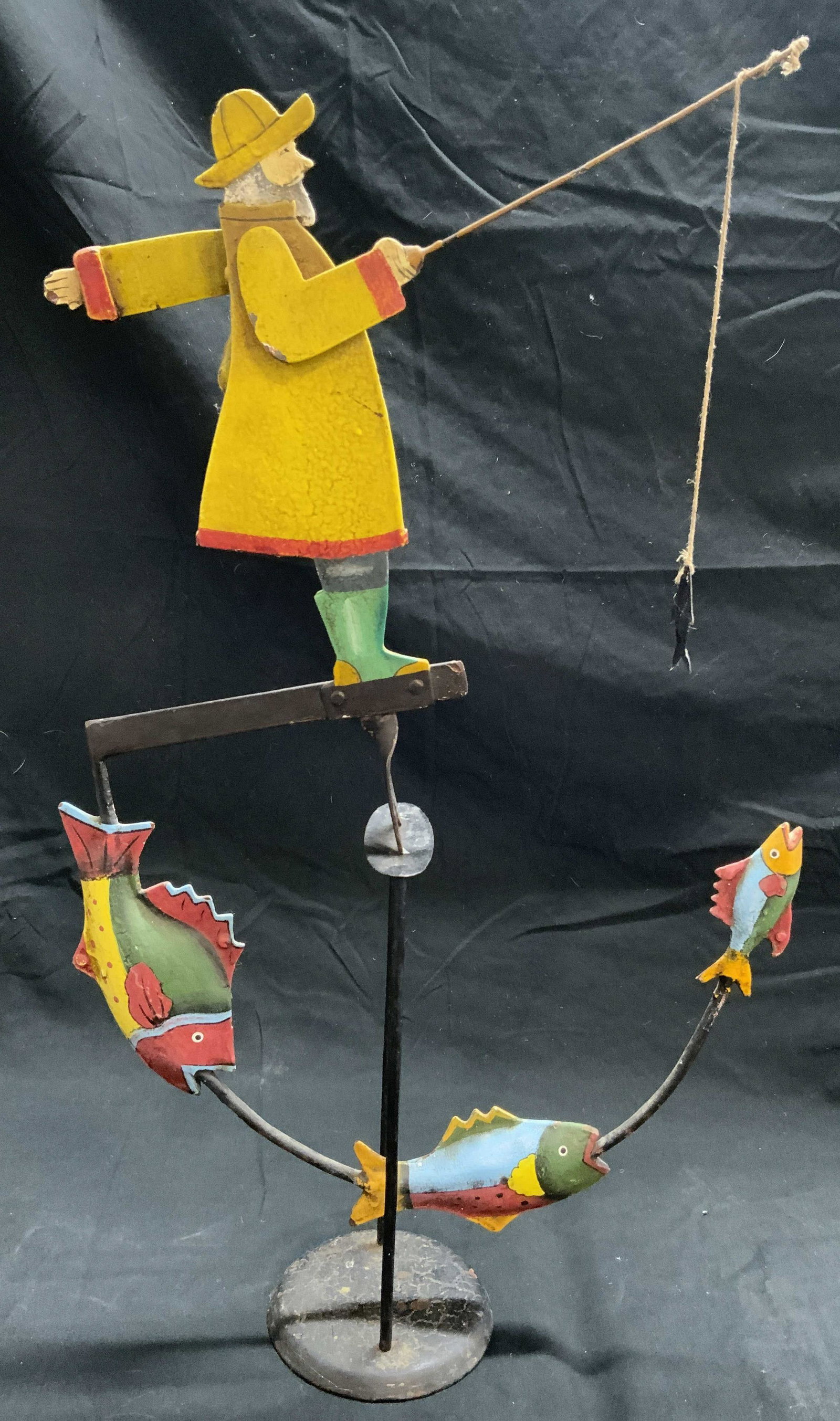 AM Antique Hand Crafted Iron Whirligig: Underside has tag which reads AM. Whirligig appears to be hand crafted & Iron. Piece is vintage possibly antique. Depicts a fisherman in yellow jacket fishing. Fisherman has articulated arms. Whirligi