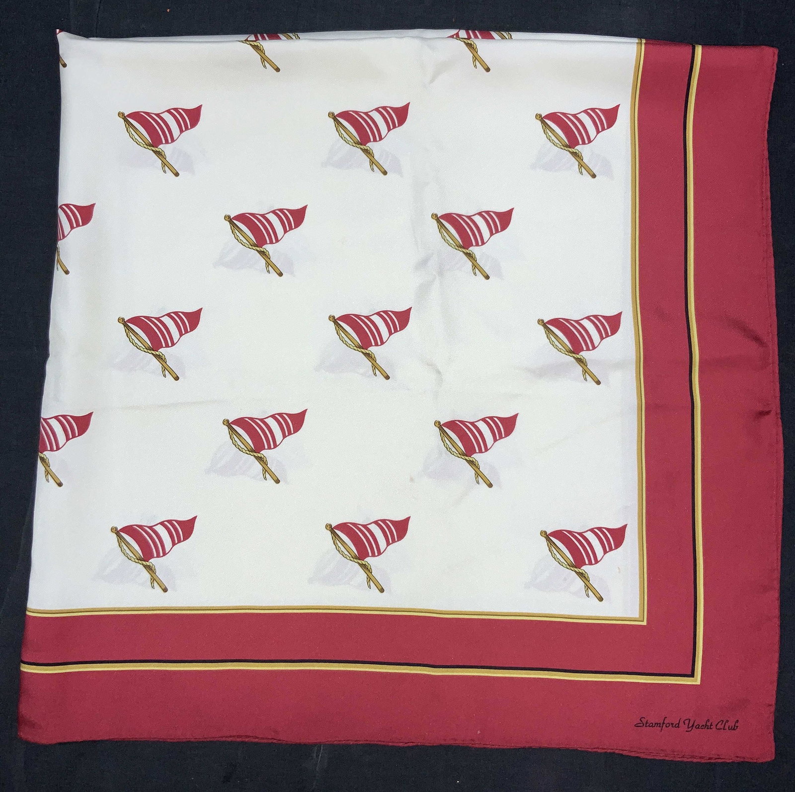 Silk Hand Rolled Stamford Yacht Club Scarf: Hand rolled edge silk scarf marked on corner Stamford Yacht Club. Soft hand, possibly silk. Scarf has red and yellow bands on edges with nautical flags on posts as center designs. Approximately 3ft x