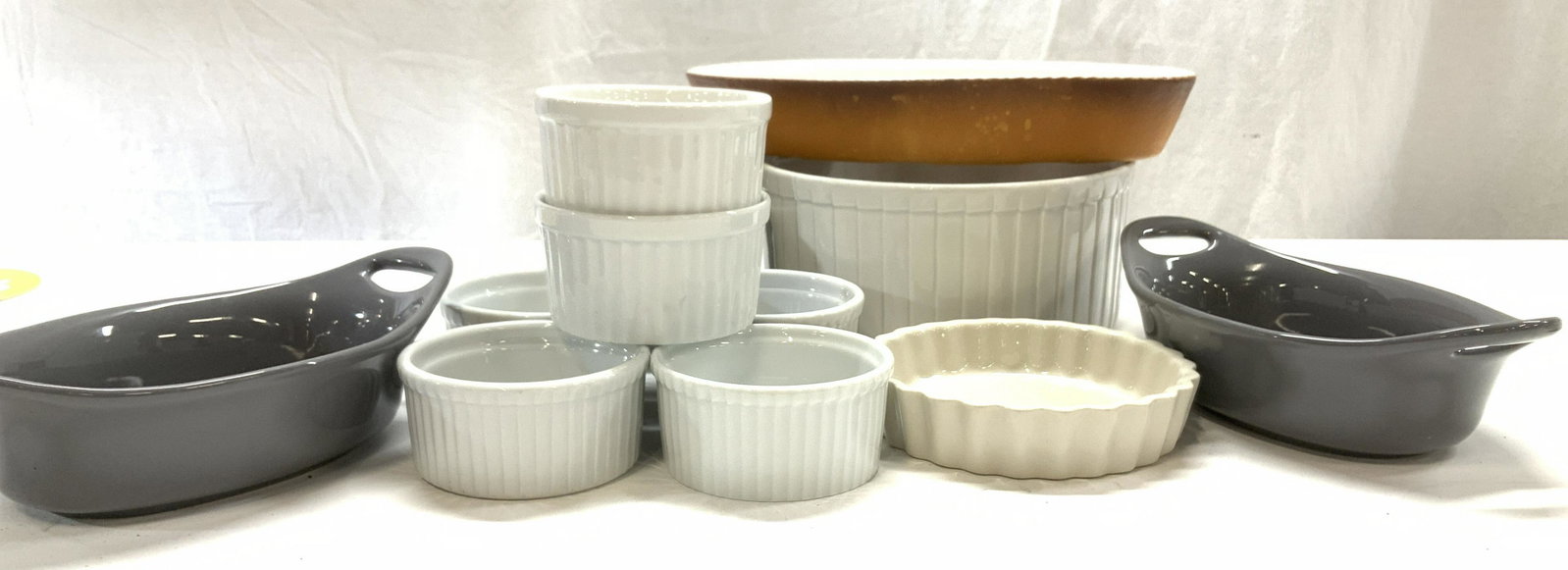 Lot13 Cookware and Serving Dishes: 8 white porcelain Ramekins, couple w surface cracks. Porcelain souffle dish 3.5 x 8 in. ( has porcelain crack ) Torte dish, 5 x 1.25 in. Pair Rachael Ray 12 oz Oval Au Gratin bowls with handles , 8 x 