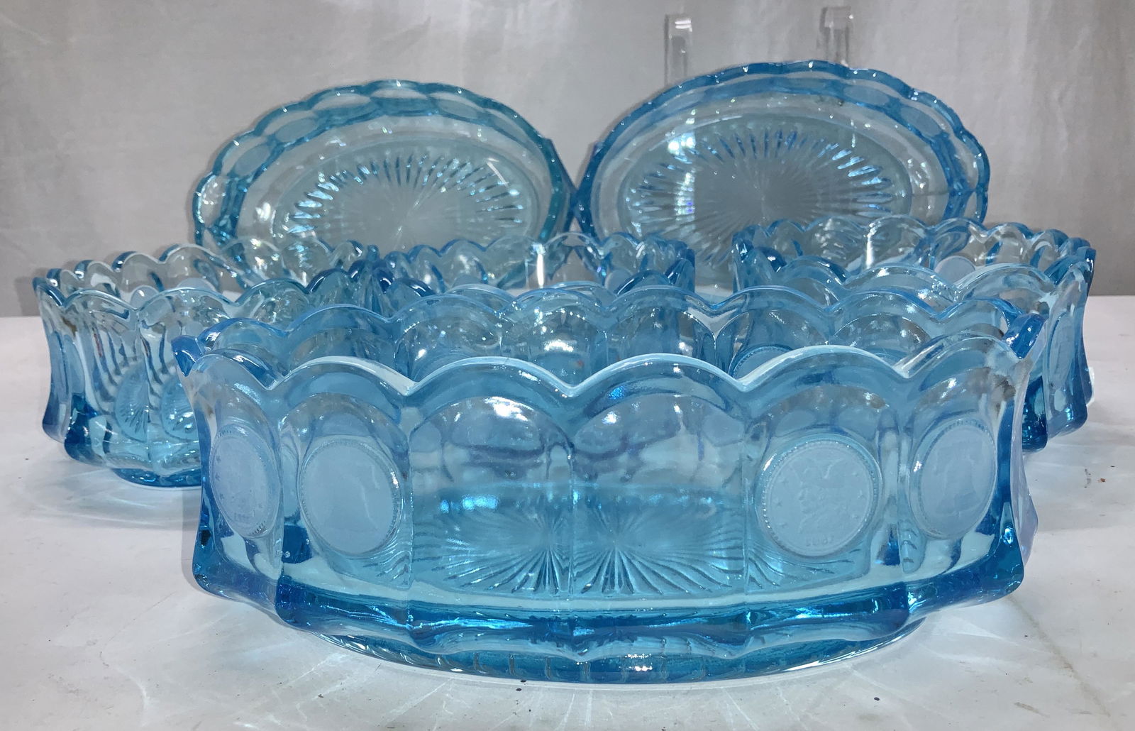 Aqua Fostoria Coin Glassware Bowls, 6: Aqua blue Fostoria coin glassware with scalloped edges and faceted sides. Coins depict liberty bell and profile of G. Washington. 3 pieces have a Fostoria label affixed, These are oval bowl, Measure 9