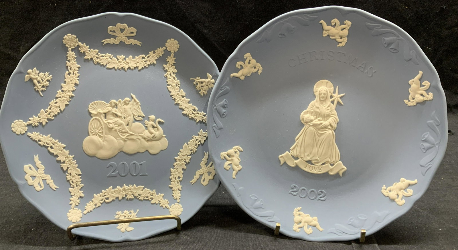 Pair Blue Wedgwood Display Plates, England: Pair blue Wedgwood display plates, 7.5 in and 7.25 in. One plate is a 2002 commemorative Christmas Plate with putti and Mary holding baby Jesus. The other has grape vine garland with bows and angles w