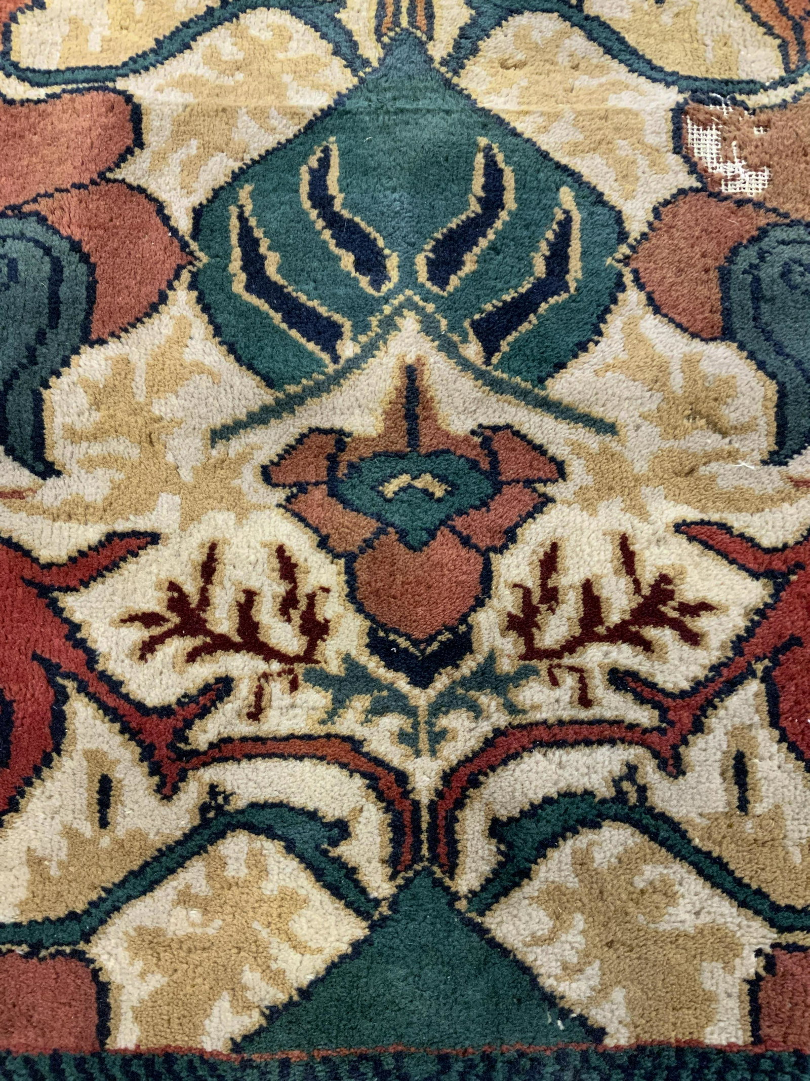 Vintage Lotus & Vine Patterned Fringe Trim Rug: A vintage fringe trim rug decorated with a lotus and vine pattern. Green, yellow, rust, red, and cream hues throughout. Possibly crafted from wool. Some losses, discoloration, and surface wear present