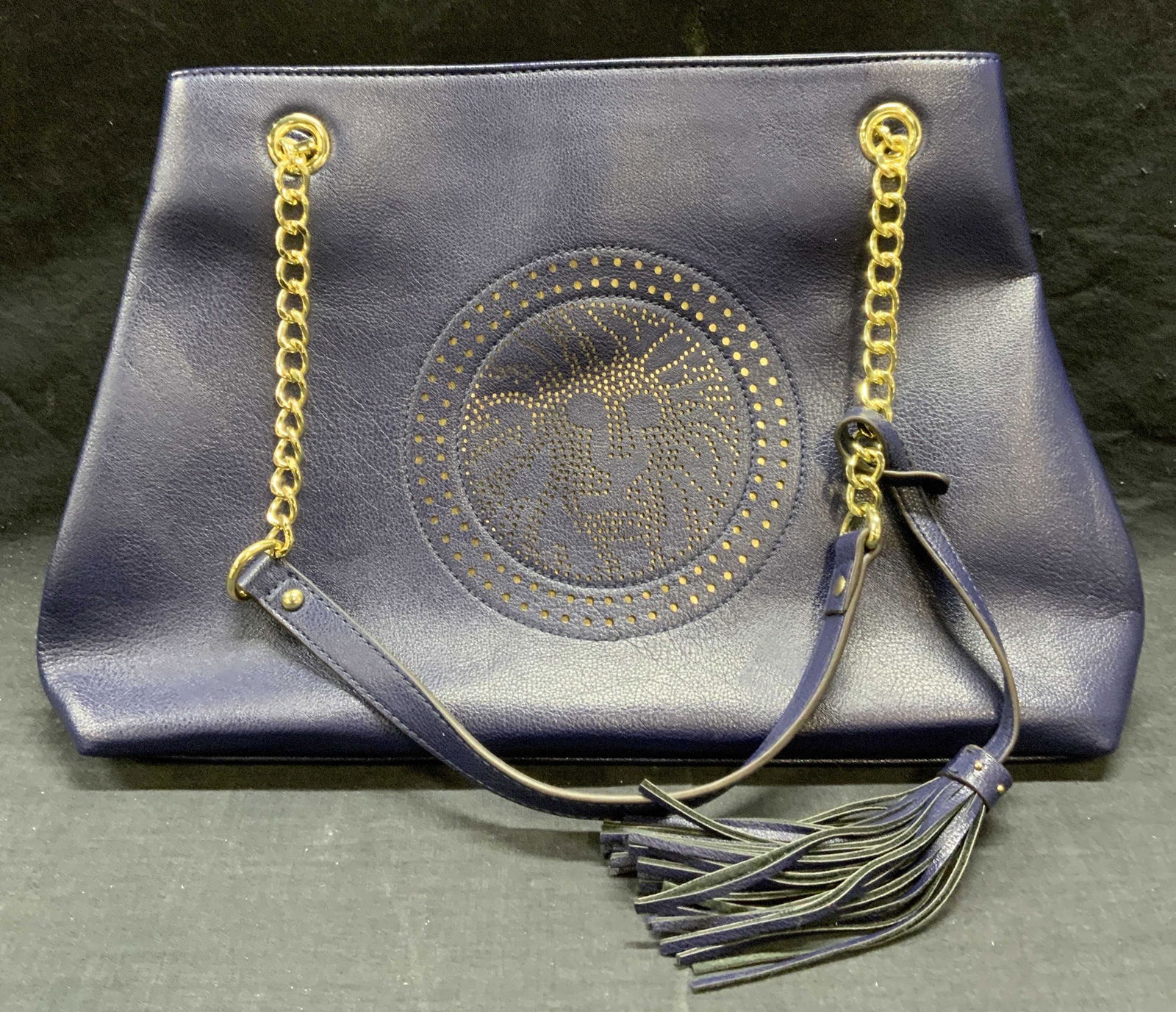 ANNE KLEIN Blue Perforated Leather Handbag: Anne Klein blue perforated leather handbag with lion logo motif. Designer label to interior patch. Snap button closure, 2 zippered pockets and 2 slip pockets to interior. Measures approx. 14.5 x 4.5 x