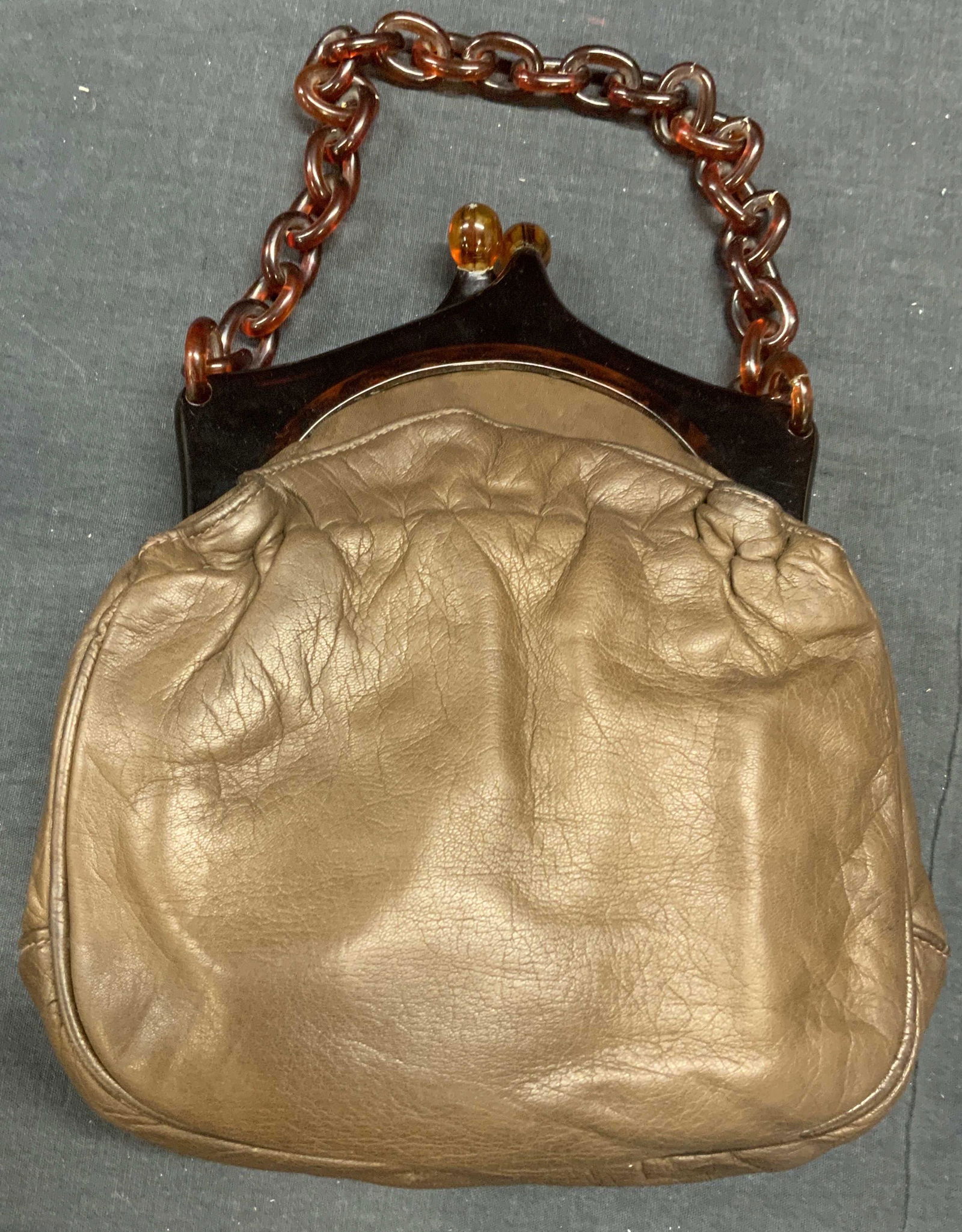 Brown Leather Handbag with Lucite Chain: Brown leather handbag with lucite chain. Kiss clasp and 2 slip pockets to interior. Measures approx. 7 x 1.75 x 7 inches. Some surface wear consistent with exposure. No labels to piece. Ladies handbag
