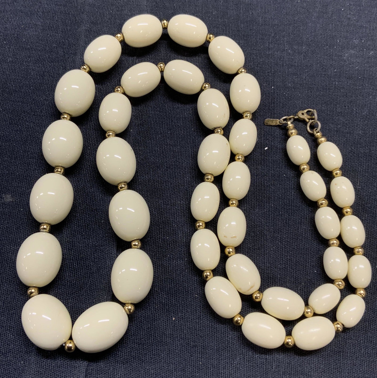 MONET Cream Graduated Beaded Necklace: Monet cream toned graduated beaded necklace with gold tone bead accents. Measures approx. 27 inches long. Designer label to jewelry charm. In good condition. Estate jewelry, costume jewelry, cocktail 