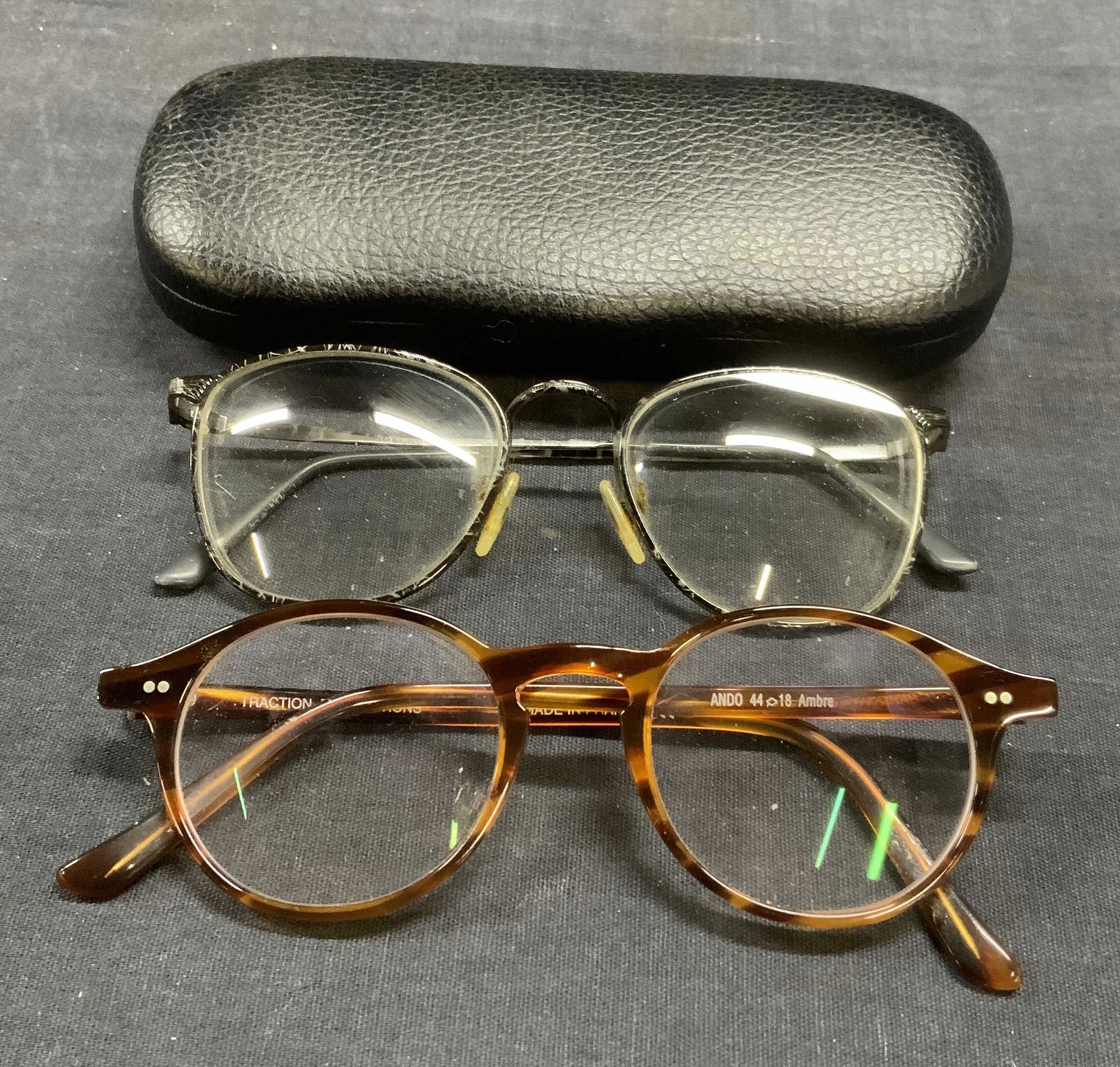 Lot 2 LOGO PARIS & TRACTION Eyeglasses, France: Logo Paris black frame eyeglasses, approx. 5 x 5.25 x 1.75 inches. Made in France. Traction Productions amber tone acrylic frame eyeglasses, approx. 5.25 x 5 x 1.75 inches. Made in France. Includes bl