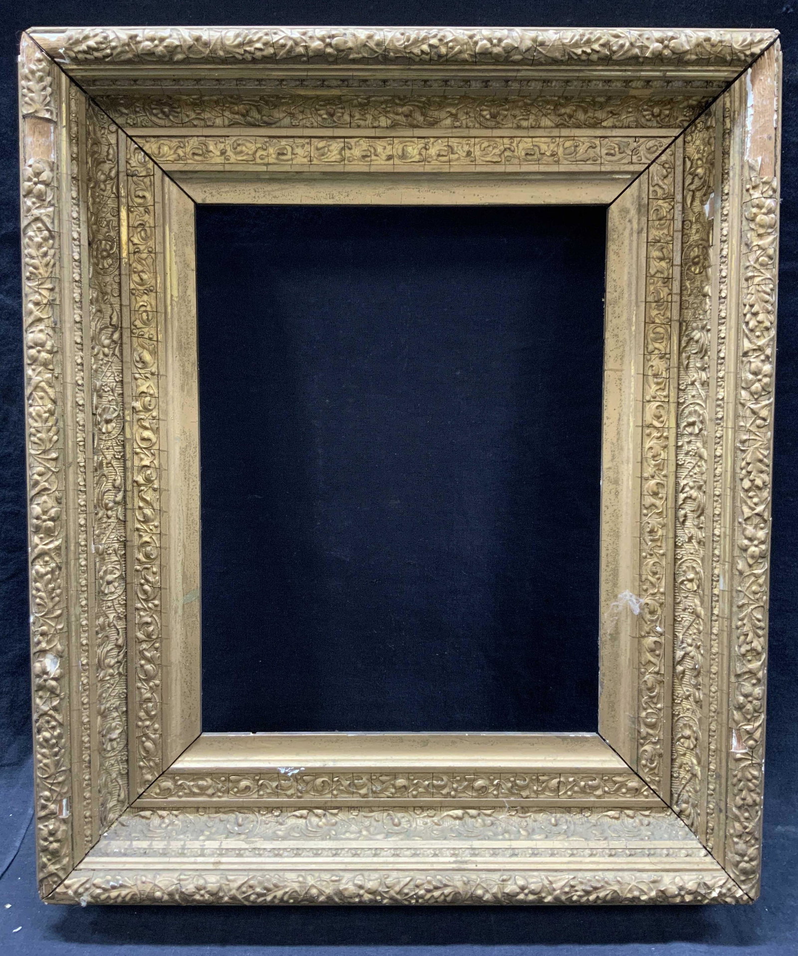 Carved Ornate Gold Toned Wooden Frame 10 x 8: Carved wooden ornate frame with floral raised motifs on outer edge and scroll patterns on inner edges. Inner edge measures 10 x 8, outer edge measures 16.5 x 14 inches. Evident wearing and loss to fra