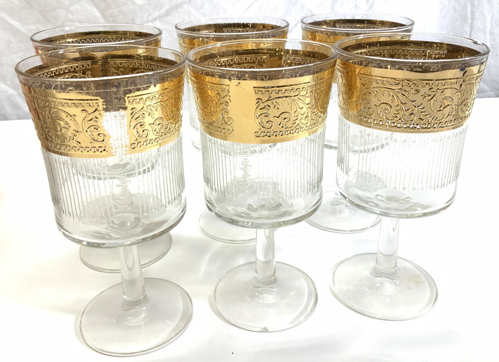 Culver STARLYTE 22K Gilt Stemware, Sgn , 6: Mid Century c. 1960s glasses with embossed 22k gold acanthus border. Signed STARLYTE on glasses, measure 6.5 x 3.25 in. A couple glasses with base or a rim chip. Culver STARLYTE Vintage Stemware, 22k