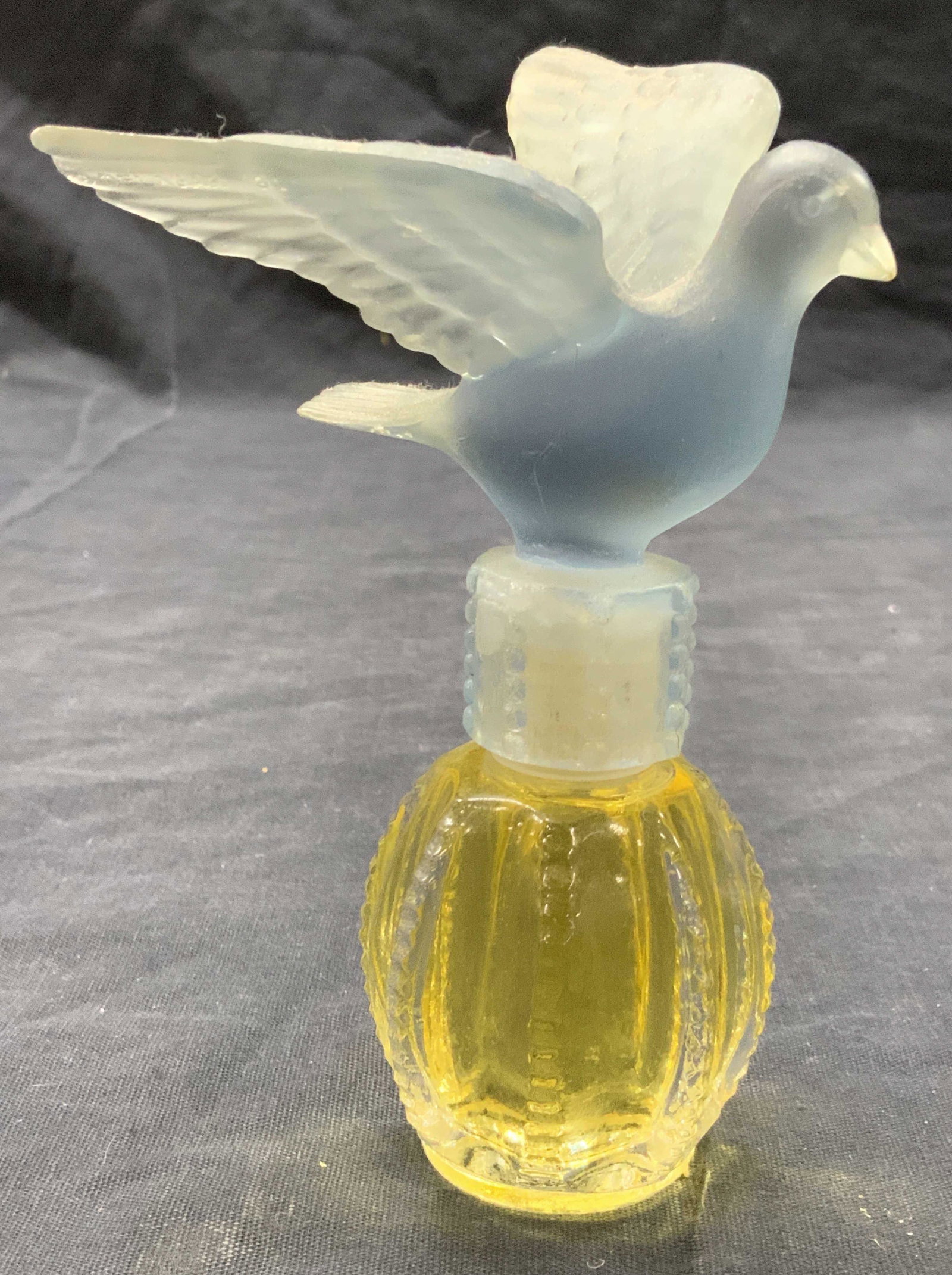 Delagar Royal Dove Perfume Bottle, 1980: Delagar branded Royal dove perfume bottle with blue resin dove shaped cap to glass bottle. Marked on underside Delagar 1980.Royal Dove. Approximately 5 inches tall. Perfume bottle is filled with perfu