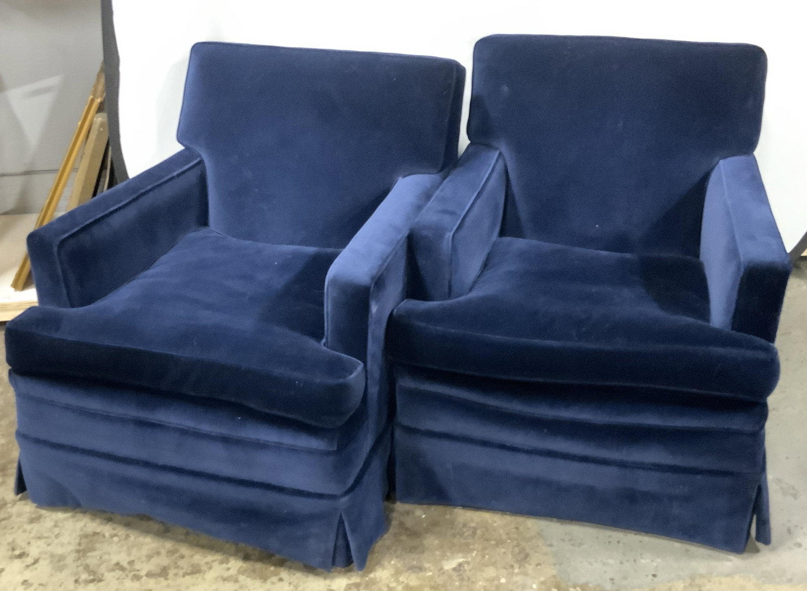 Pair Blue Velvet Upholstered Armchairs: A pair of deep blue velvet upholstered armchairs. Skirted. Removable seat cushions. Measures approx 31H x 35D x 29W in. Some losses present. Some discoloration. Some surface wear. Armchairs, chairs, f