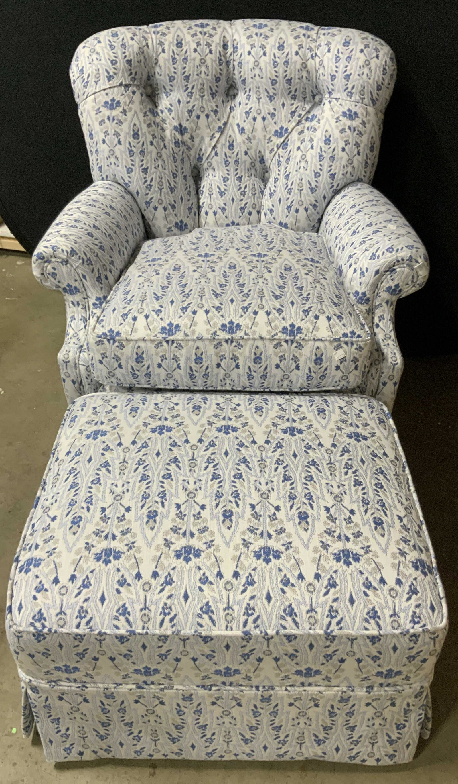 Floral Upholstery Rocking Armchair W/ Ottoman: Armchair and ottoman. Armchair rocks. Ottoman is wheeled. Skirts to both pieces. Both pieces feature floral upholstery. Blue, white, and silver hues. Armchair has removable seat cushion. Armchair is t