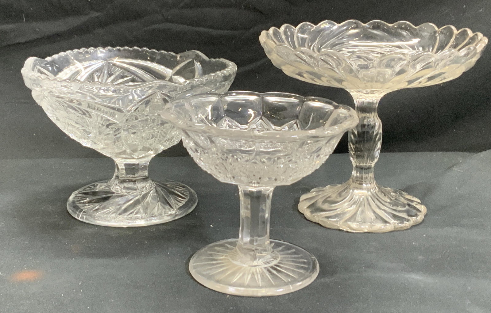 Lot 3 Mid Century Glass Tazzas: Vintage mid century clear glass Tazzas. Multi pattern. 2 are footed bowls. Sawtooth rim style measures 4.5 x 6.25 in. Tazza dish with scalloped rim measures 5.5 x 6.25. Candy Tazza, Glass Footed Tazza