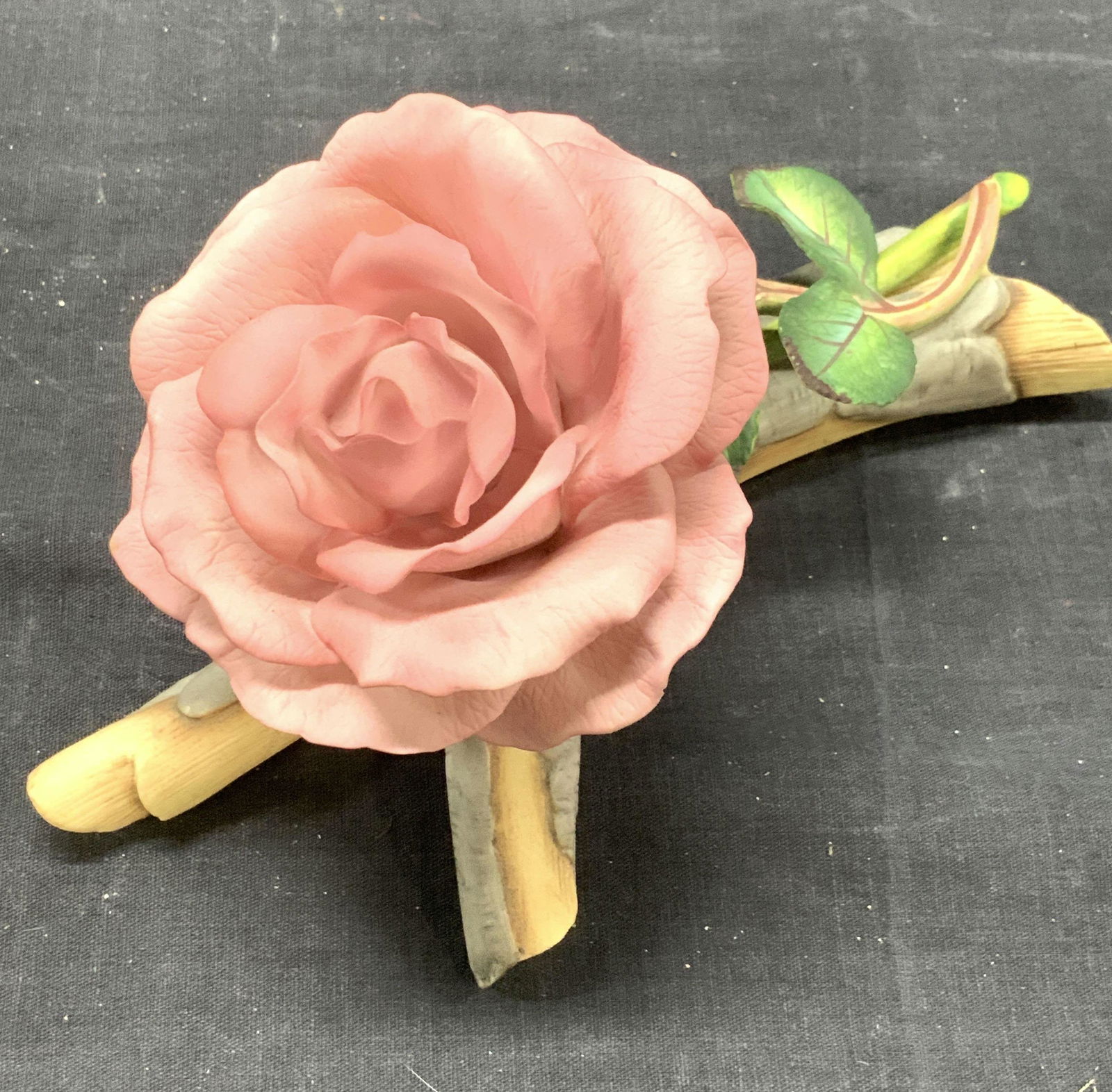 Ron vanRuyckevelt Porcelain Rose Sculpture England: Pink Rose Sculpture with green stem resting on a grey branch. From the Royal Horticultural Society , titled THE QUEEN ELIZABETH ROSE. sculptured by Ronald van Ruyckevelt c. 1981. Measures 8.25 x 5 x 4