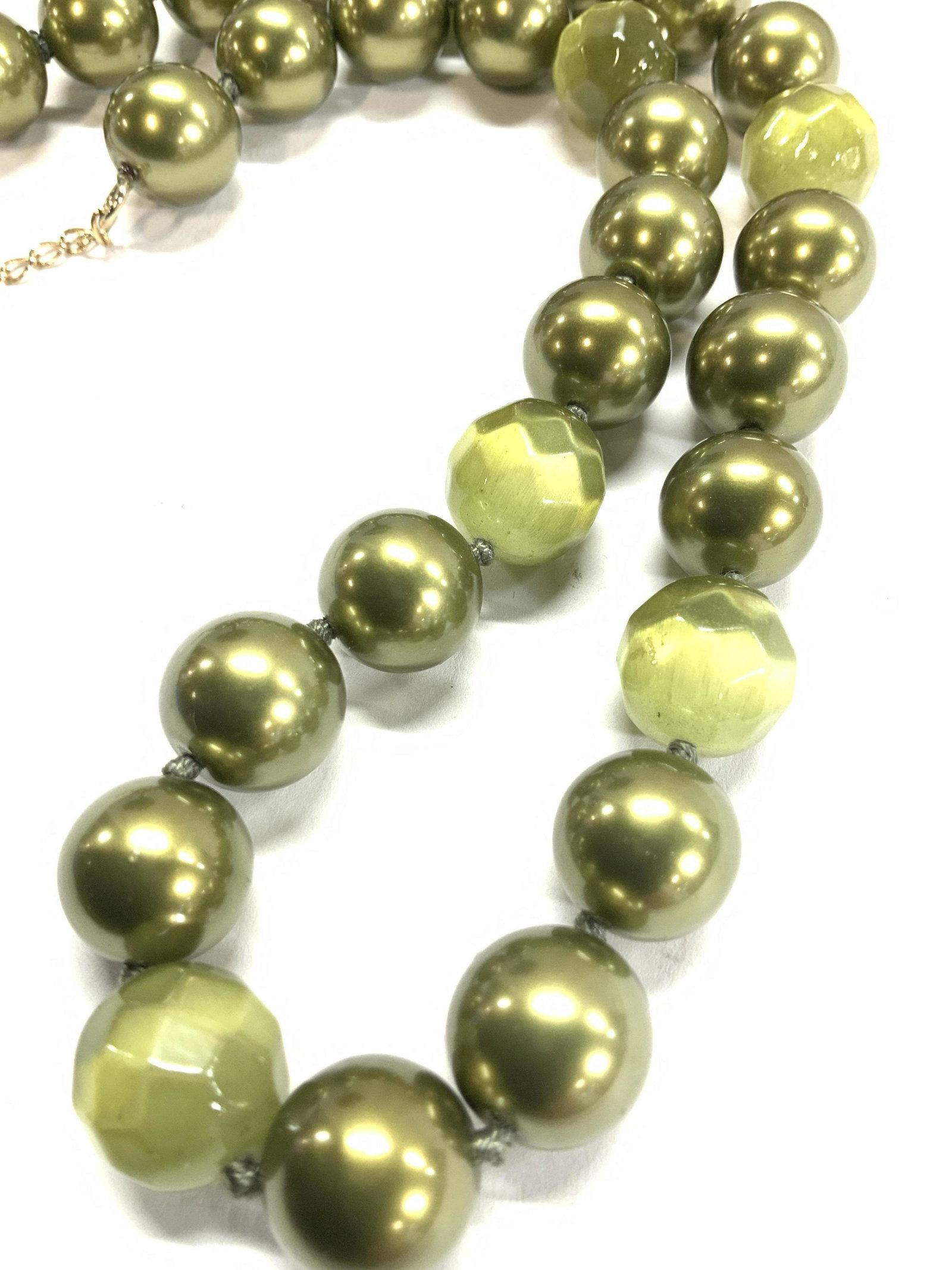 MONET Costume Pearl Necklace in Olive: Stylish statement pearlescent and glass bead necklace with hook clasp. Each pearl measures app 13 mm, double knotted and has interspersed faceted glass beads that resemble green tigers eye. 16-17.5 in