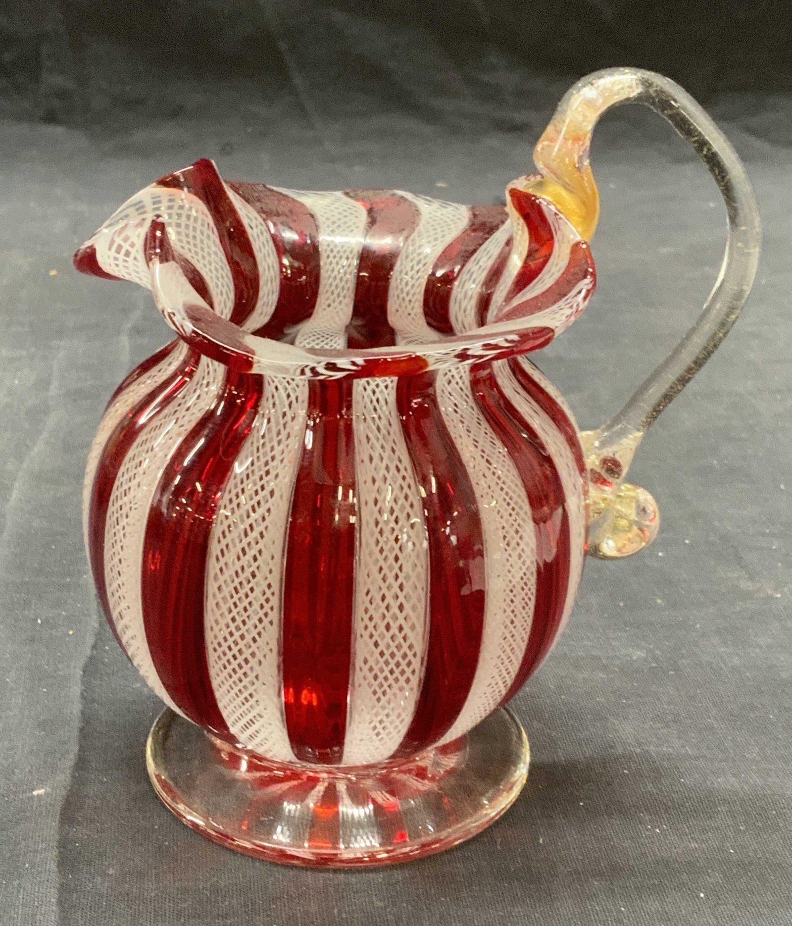 Fenton Style Red/White Striped Art Glass Creamer: Fenton style red and white striped Art glass creamer. Some surface wear consistent with exposure. Measures approx. 4.5 x 3.75 x 5 inches. Art glass, art glass creamer, Fenton style creamer, Studio gla