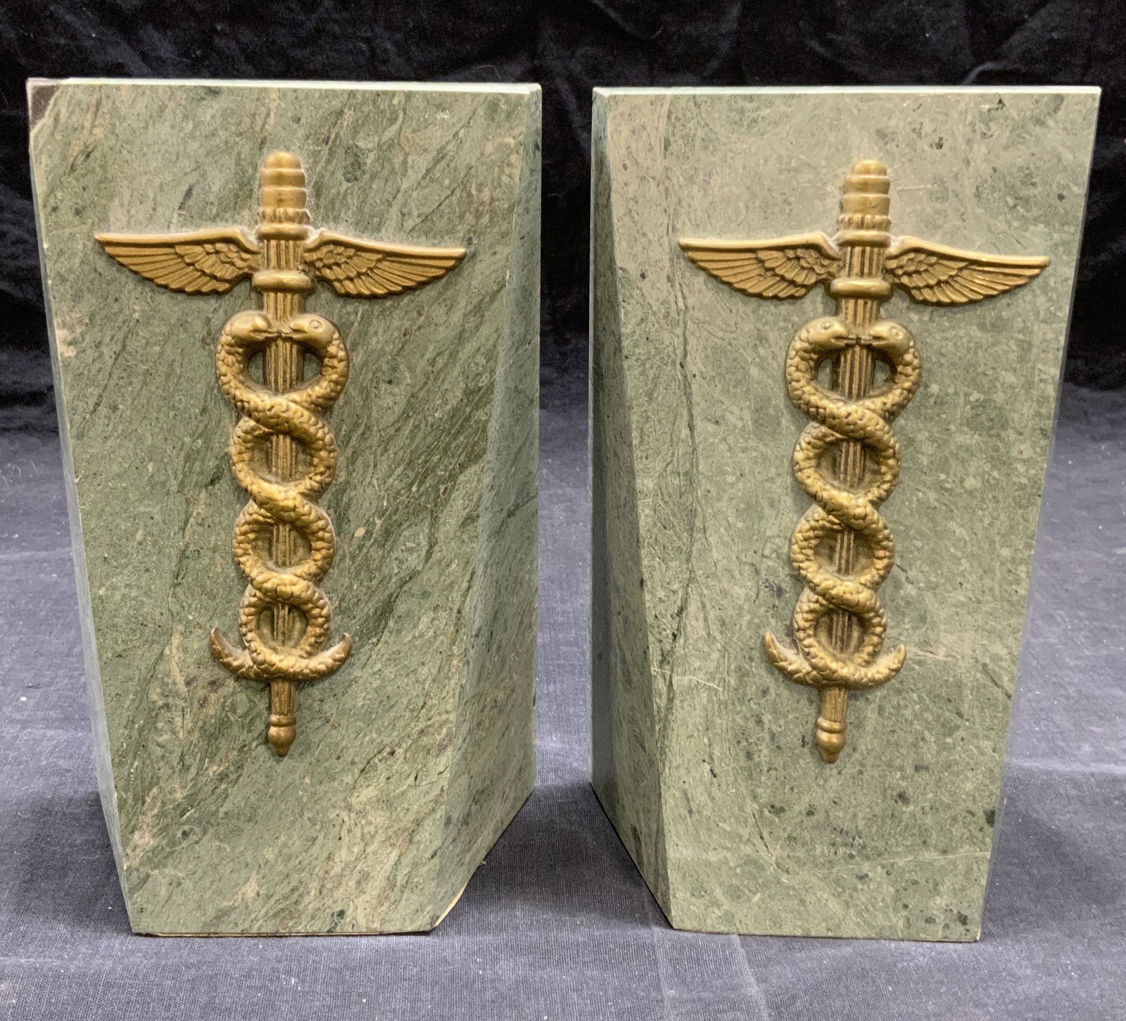 Decorative Crafts Enameled Medical Bookends: Decorative Crafts Inc green marbleized enameled metal bookends with brass Staff of Hermes medical symbol. Some chipping observed. Measure approx. 5 x 2.75 x 8 inches. Trademarked to underside of 1 boo