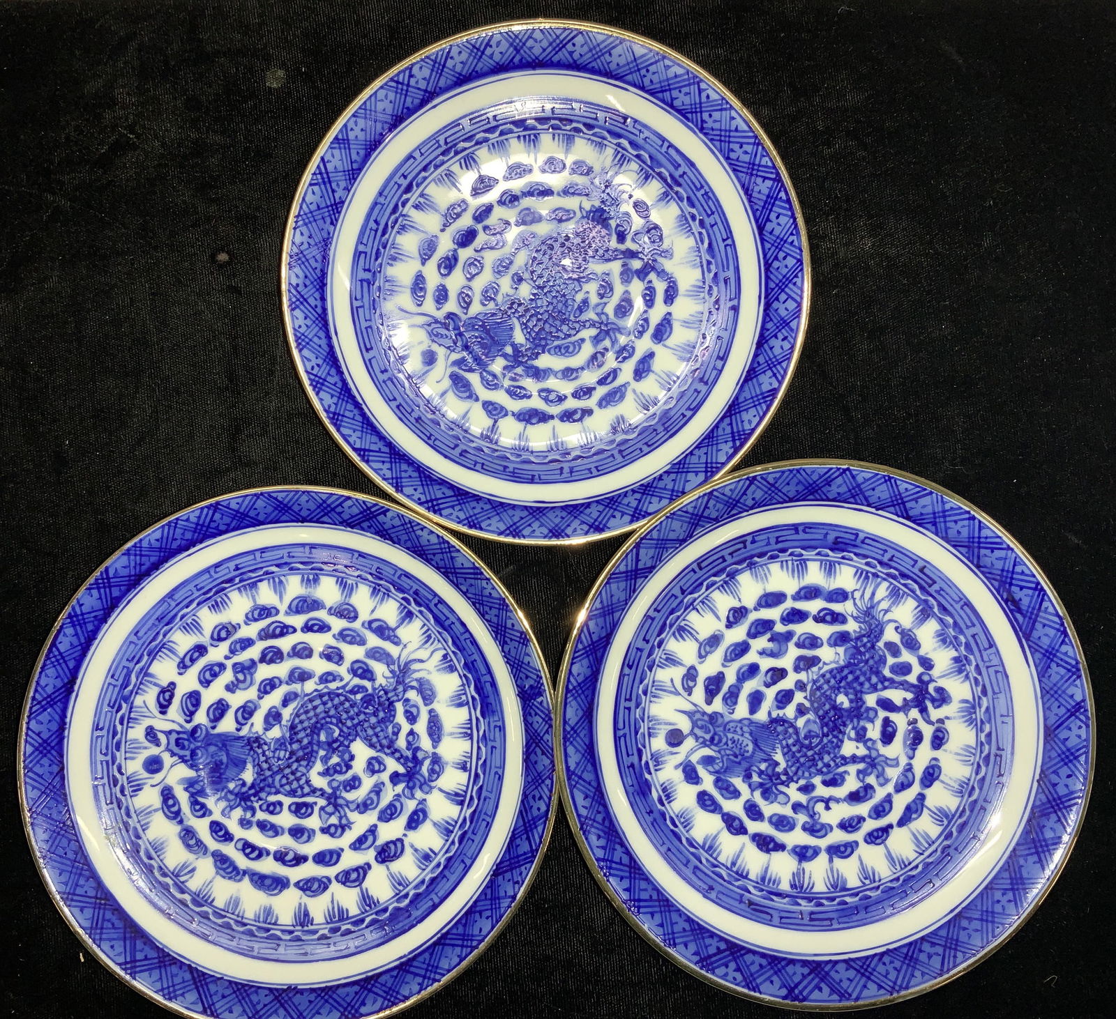 Set12 Hand Paint Porcelain Dragon Plates Hong Kong: Blue and white tea cup saucers/ plates , hand painted with 24k gilt rim. Center motif of Chinese dragon amongst lei-wen clouds, and Tao-tie border . 5.25 in. Hallmarked Decorated in Hong Kong. Decorat
