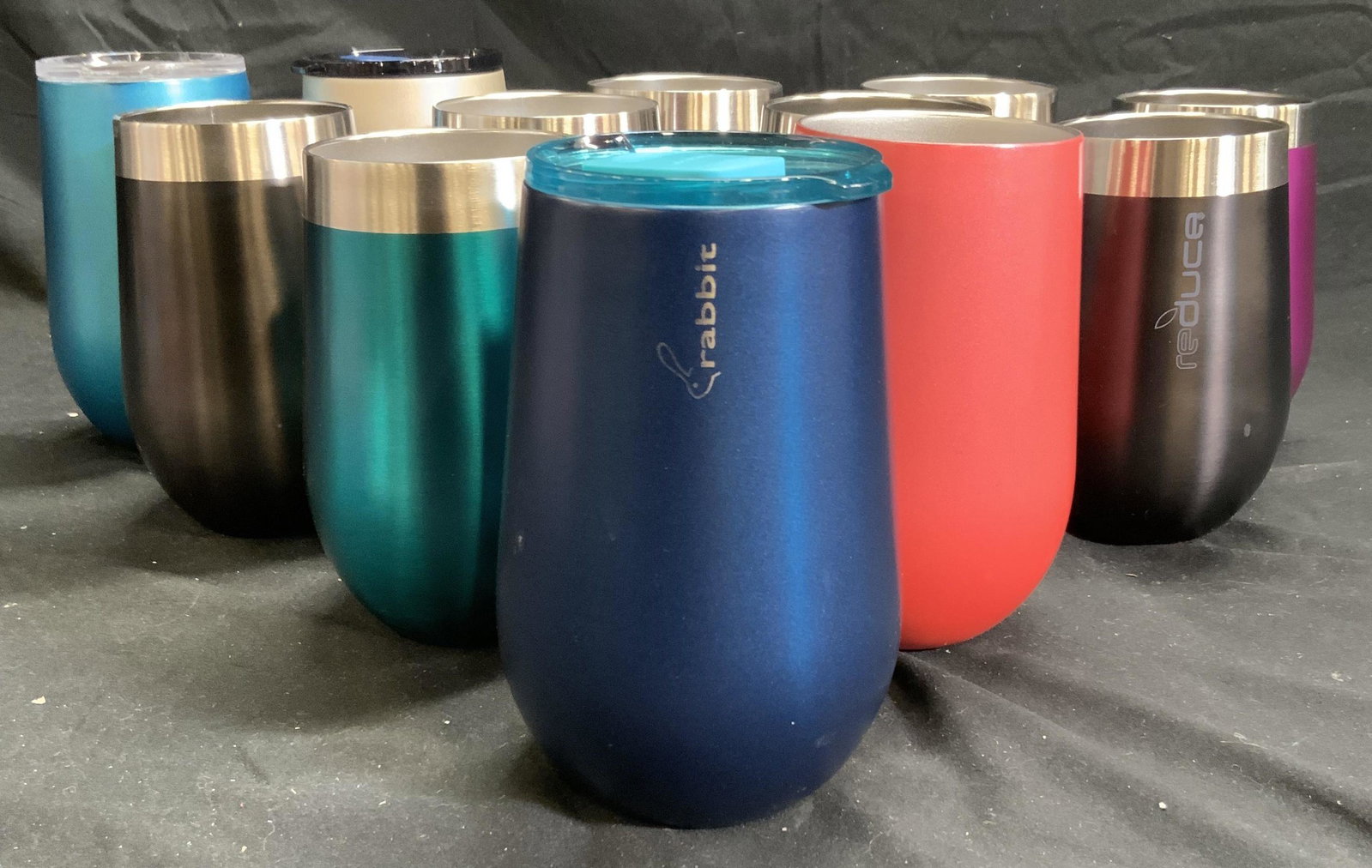 Lot 12 Assorted Metal Tumblers Vessels: Lot includes 8 tumblers trademarked REDUCE & 4 Tumblers trademarked RABBIT. Lot includes black, red, navy, aqua and more. Each appear to be brush metal/ stainless steel. Each tumbler measures approx 5