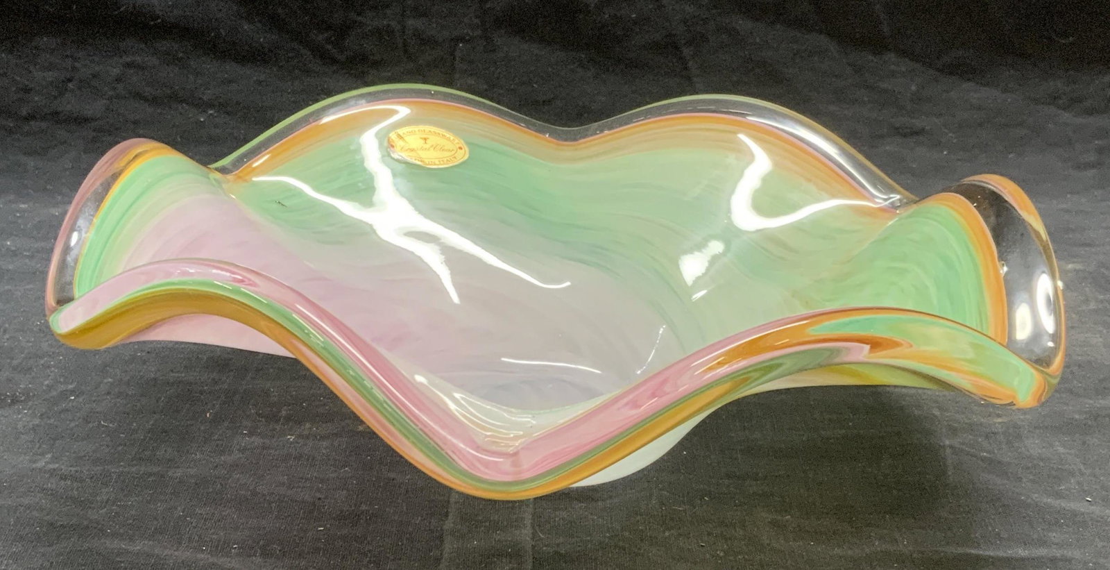 MURANO Swirled Art Glass Bowl, Italy: MURANO green, purple, and orange toned swirled art glass bowl with handkerchief rim. Measures approx. 10.75 inches diameter and 3 inches tall. In good condition. Trademarked on sticker. Made in Italy.
