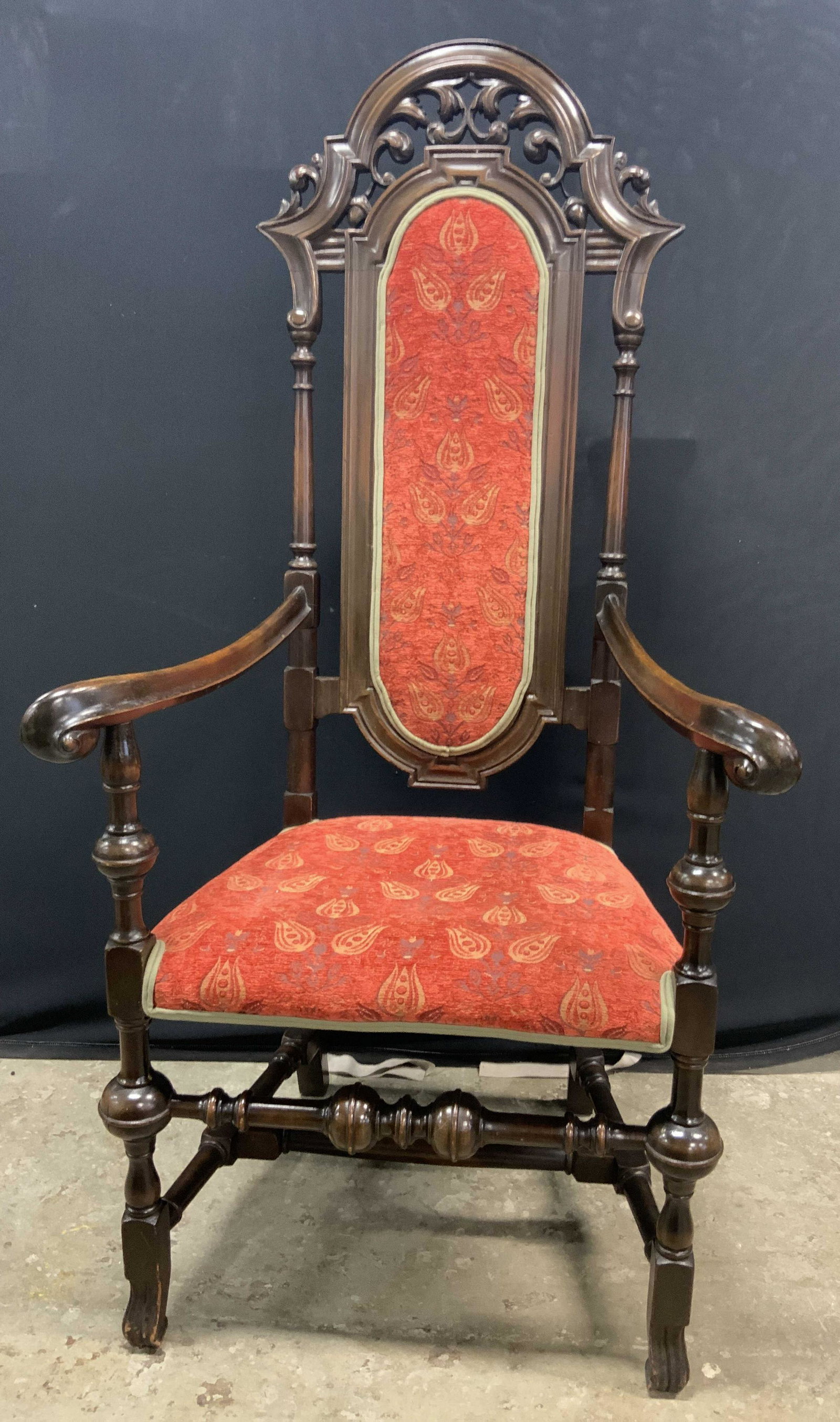 Antique English Carved Wooden Armchair: Heavy hand carved antique, possibly vintage, armchair with soft hand red upholstery. Floral motif to the upholstery. High back. Curled arms. Piece appears to be English. Measures approx 55H x 27W x 20
