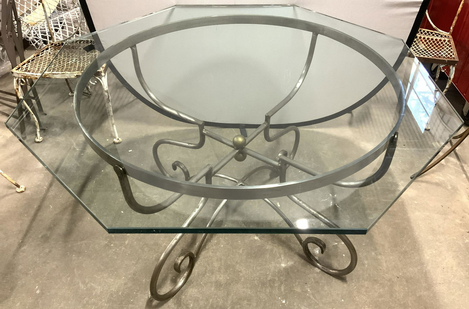 Brushed Metal Base Octagonal Glass Top Table: Table has thick octagonal shaped glass top. Piece has brushed metal base with gold toned spherical shaped structure in center. Table measures approx 30 inches tall 49 inches wide. Dining table, glass