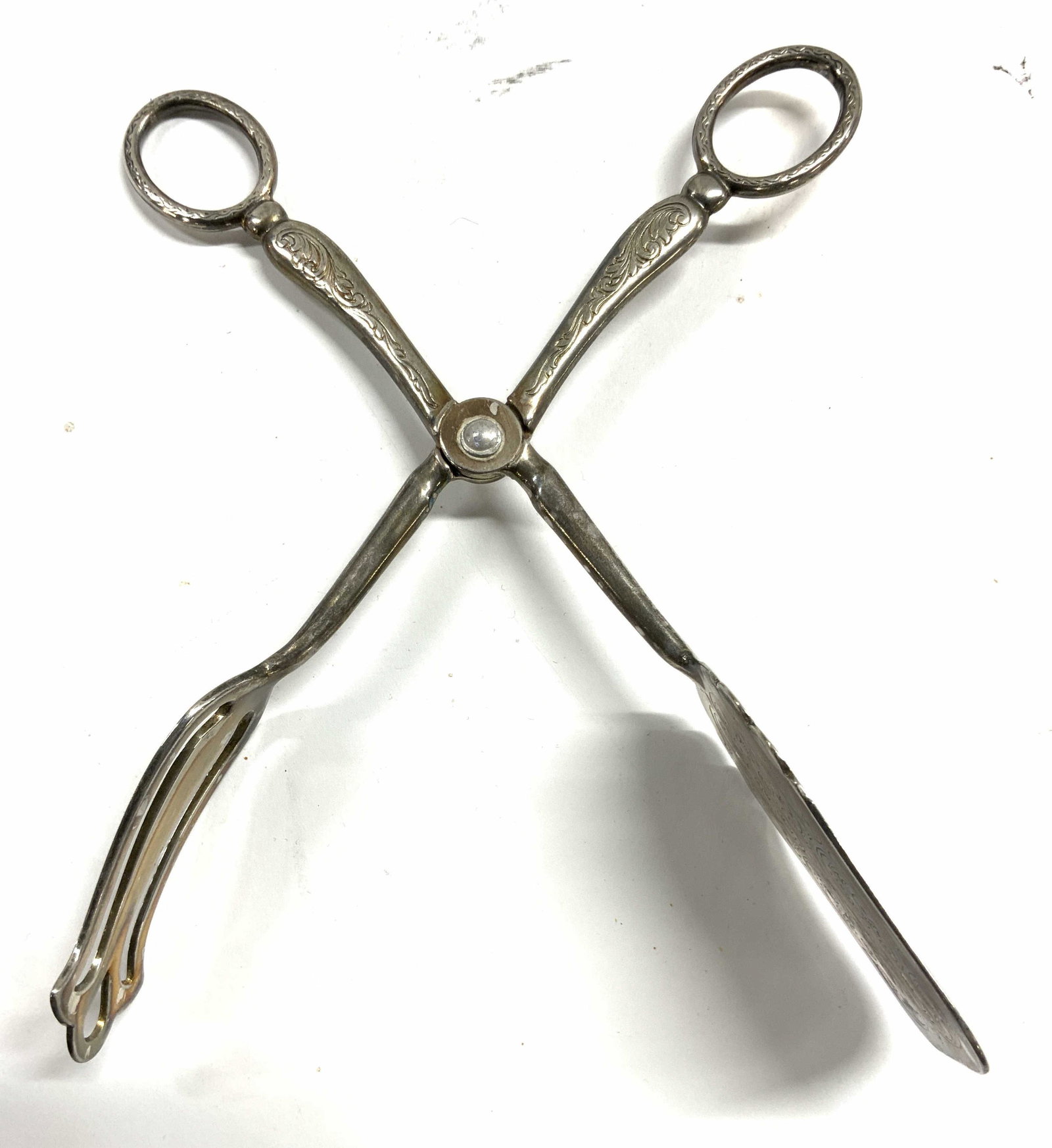 Silverplate Vintage Dessert Tongs: Dessert tongs are inscribed SILVERPLATE. Tongs have intricately etched scroll detail with scissor style handles. Piece when fully open measures approx 6.75 inches tall 5.25 inches wide. Tongs, dessert