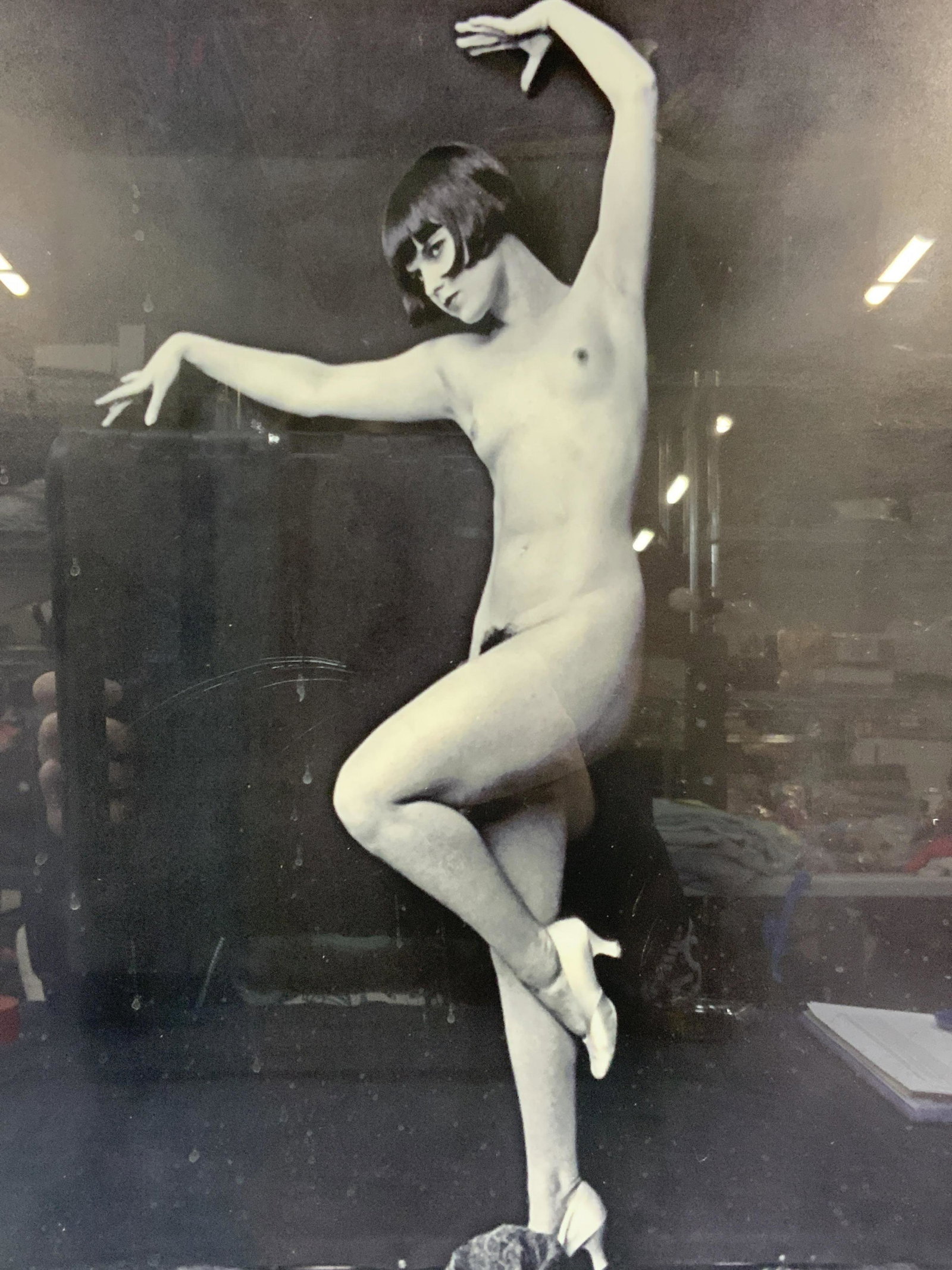 Black & White Gelatin Nude Figural Photo: Black and white photo, possibly gelatin photo depicting a nude woman in white high heels in a dynamic post against a black background. Framed in minimalist black metal frame with no mat board, under g