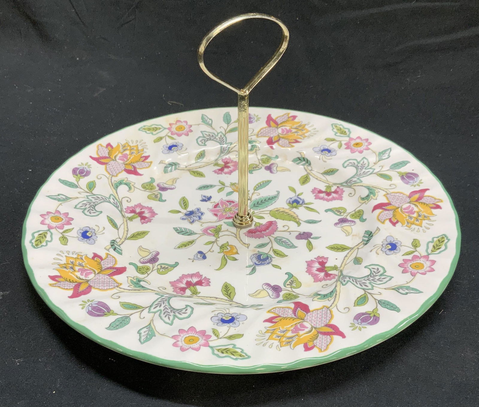 MINTON Floral Porcelain Dessert Tray England: 10.5 in. Haddon Hall dessert tray/ sandwich tray by Minton, hand painted porcelain with colorful florals on white background and green edge. Brass handle 5 in. Ht. Signed on verso, illegible Center Ha