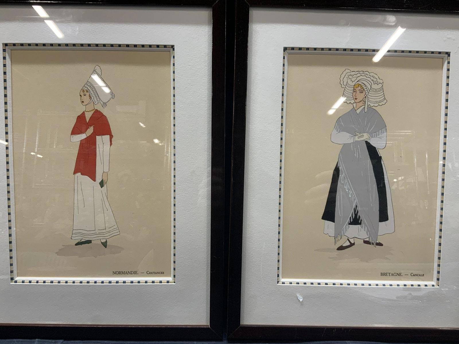 2 French Fashion Nomandie & Bretagne Silk Screens: Both marked on backsides Sharon Boudet. 2 silk screens depicting girls in vintage french fashion. 1 is marked Normandie -Coutances and the other reads Bretagne - Cancale. Both are framed in sleek brow